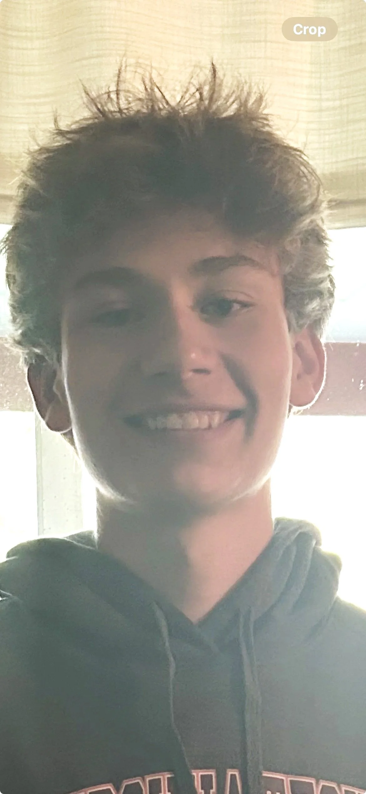 A rugged mountain landscape with colorful, weathered rocks, patches of snow, and steam rising from the ground under a cloudy sky.