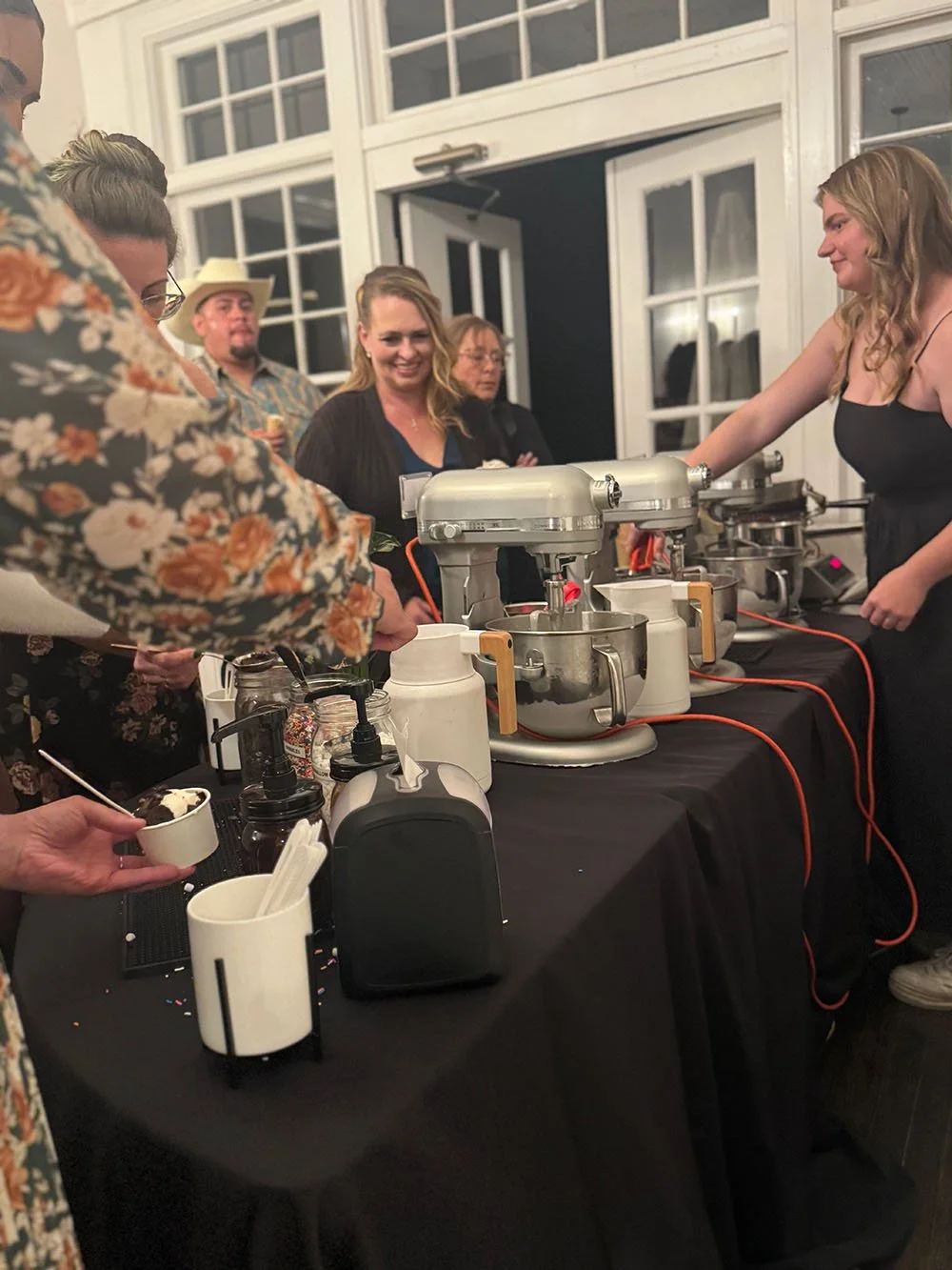 People serving and enjoying ice cream at a dessert station in an indoor setting event, catered by Polar Bros Nitro Ice Cream.