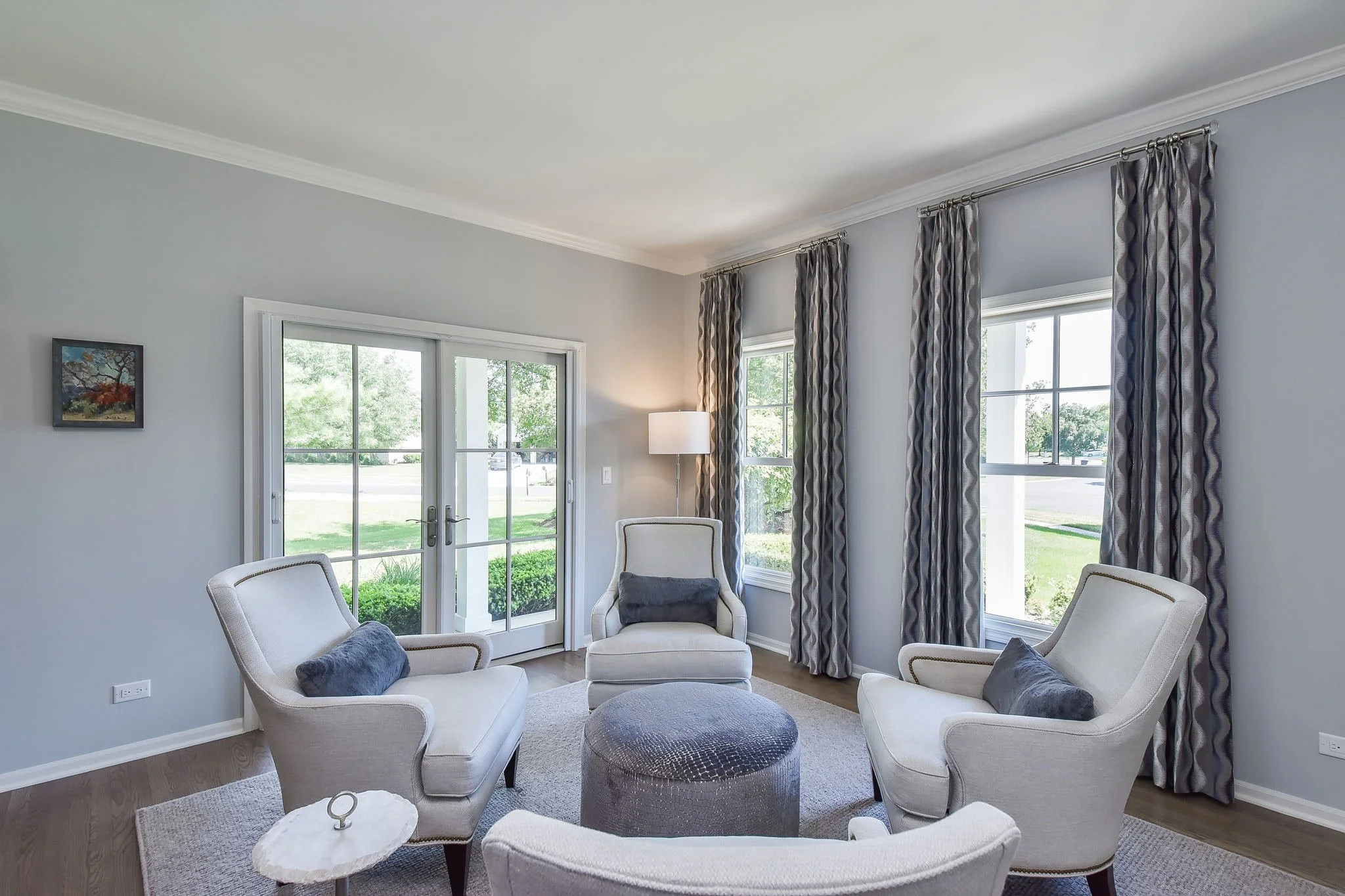 Custom lumbar pillows in color coordinated room matches custom drapery with  in an inviting, cozy living room sitting area. Light filters in through large windows.