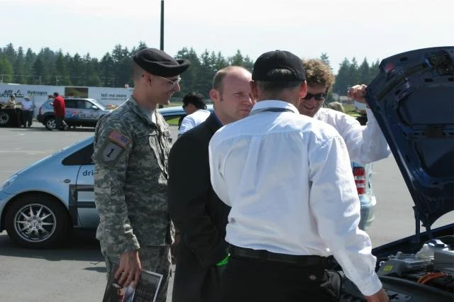 JOINT BASE LEWIS-MCCHORD SUSTAINABILITY PROGRAM WA State Representative Zachary Hudgins is shown the engine of a hydrogen fuel cell vehicle during the June 2009 West Coast Hydrogen Road Tour. The tour (from California to British Columbia) stopped at JBLM to encourage hands-on education. 50 people including Soldiers, family members, retirees, and government employees test drove 12 hydrogen fuel cell vehicles and talked with tour experts. (Photo Credit: Karli Steffy) VIEW ORIGINAL