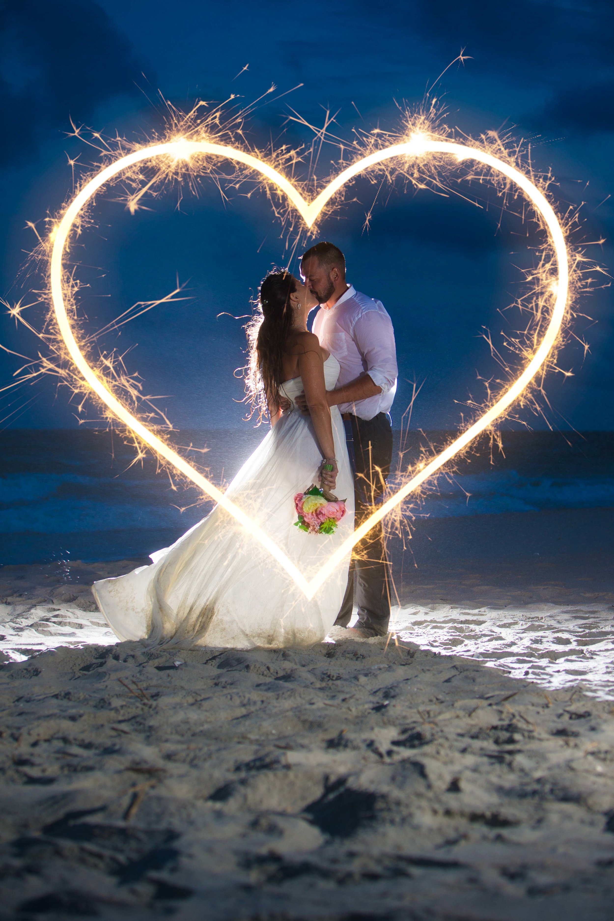  Long exposure shot of bride and groom kissing on Myrtle Beach surrounded by sparkler heart 