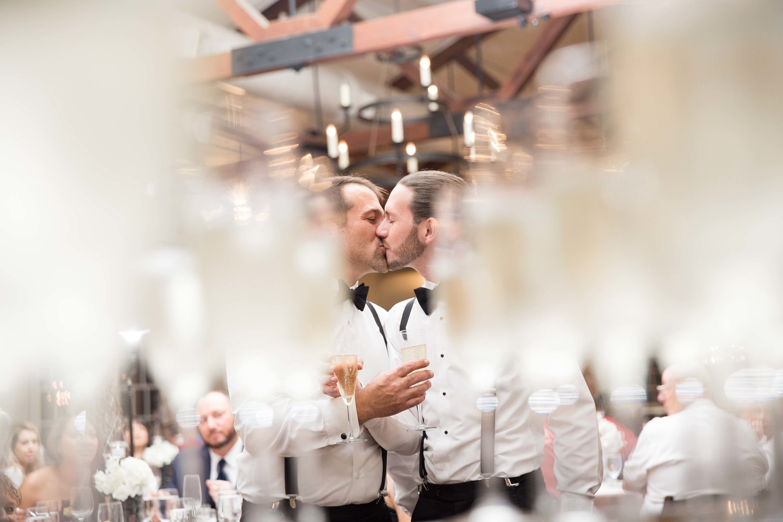  Groom kisses groom during champagne celebration after ceremony 