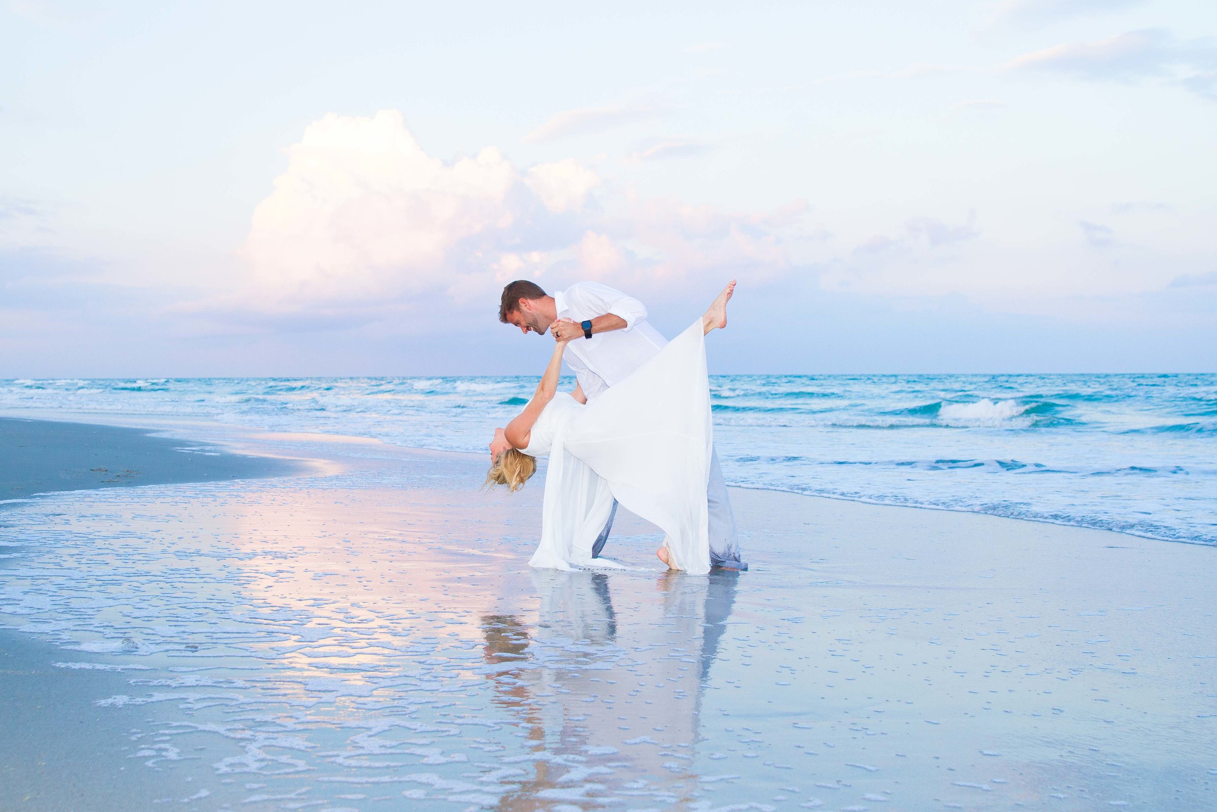  Husband dips his new wife while dancing on the blue beach 