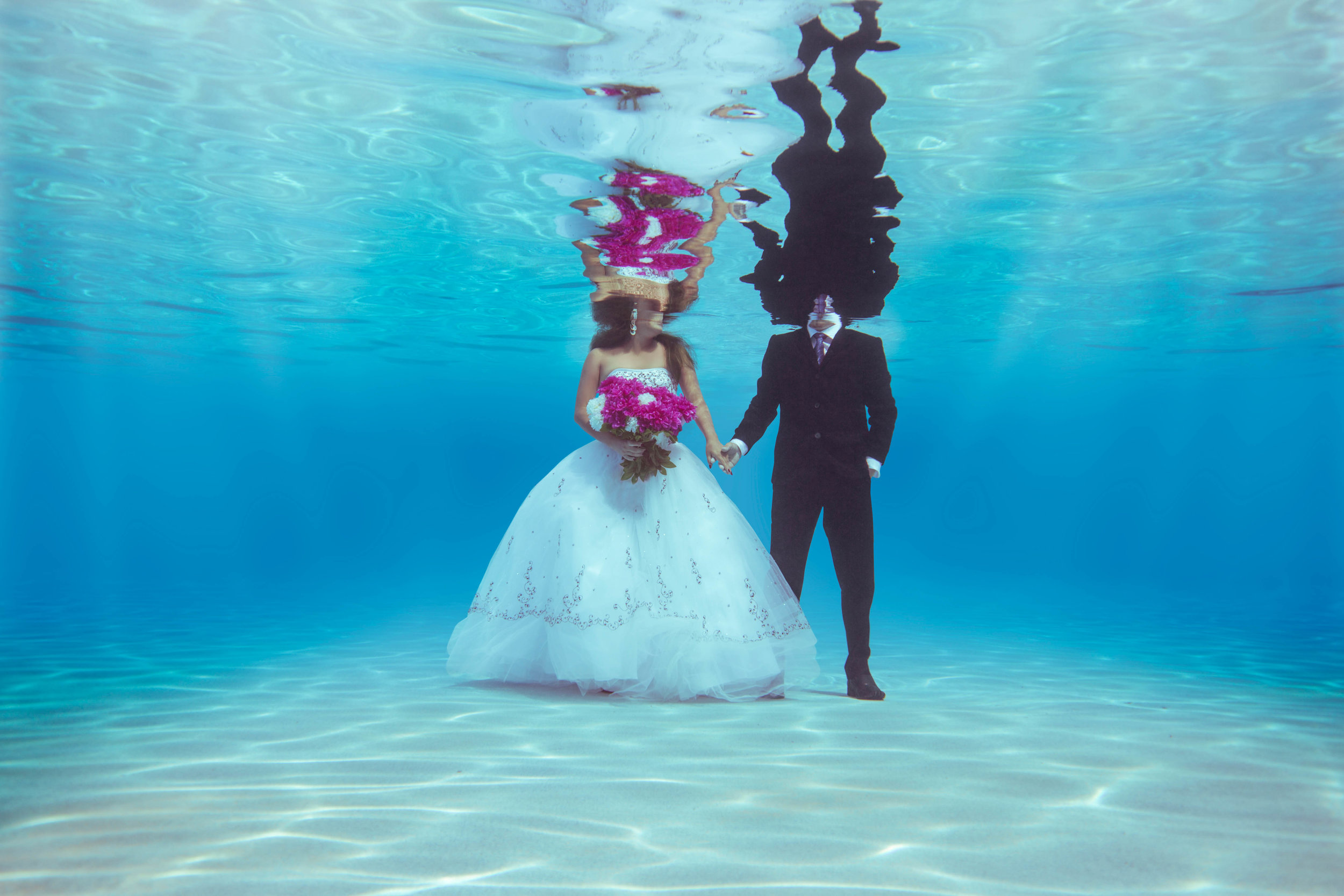  Bride and groom in dress and tux under the water 