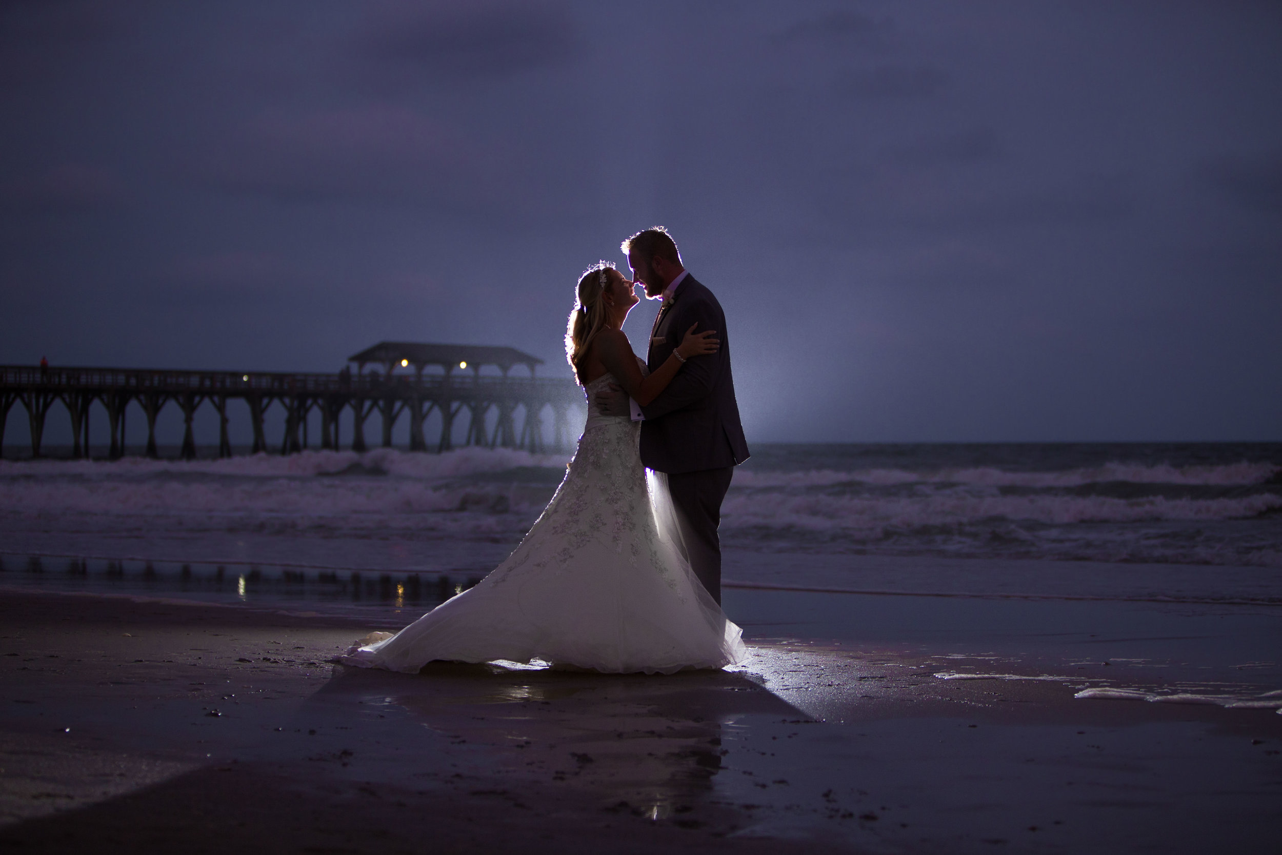 Wedding pictures of Couple kissing at  night at Myrtle Beach Springmaid Pier with the ocean behind them