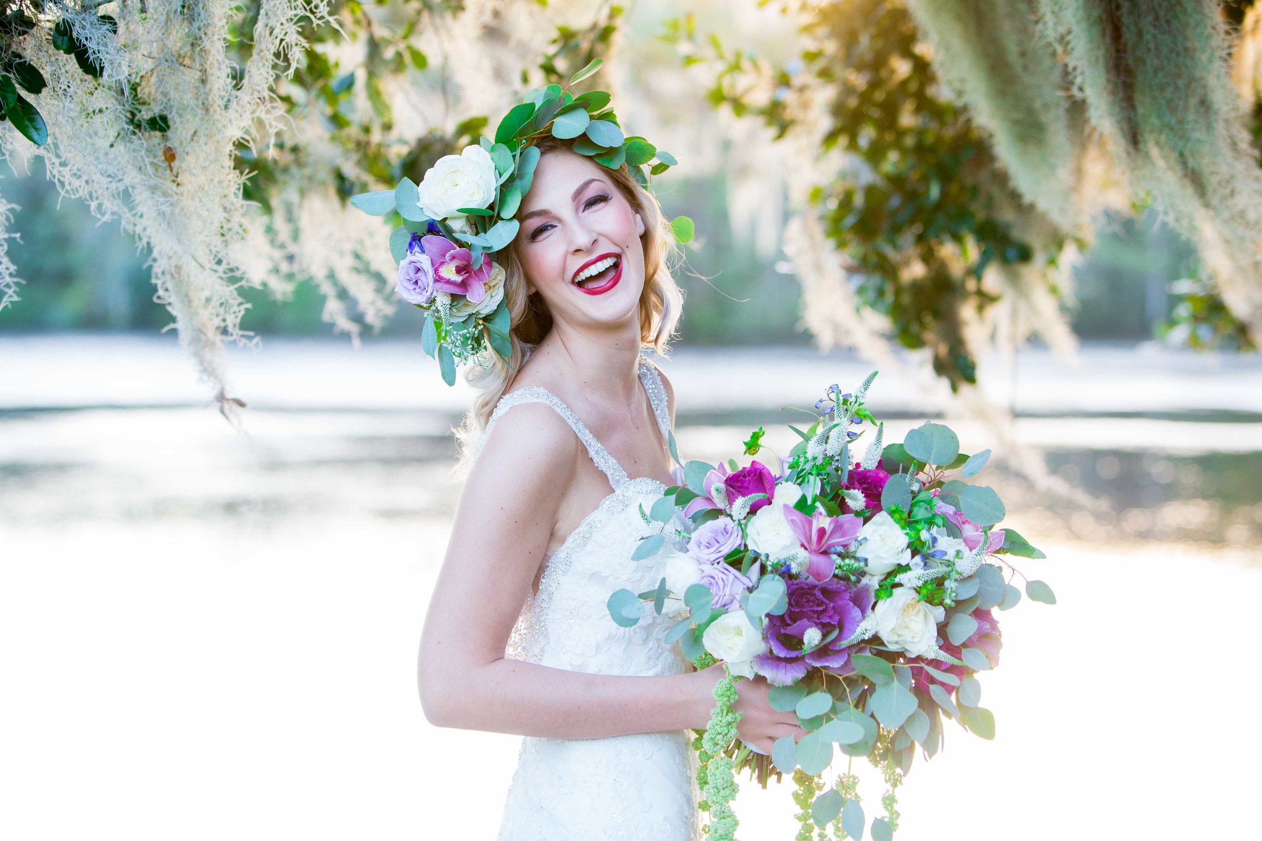  Bride smiles while looking into the camera holding a lush bouquet. 