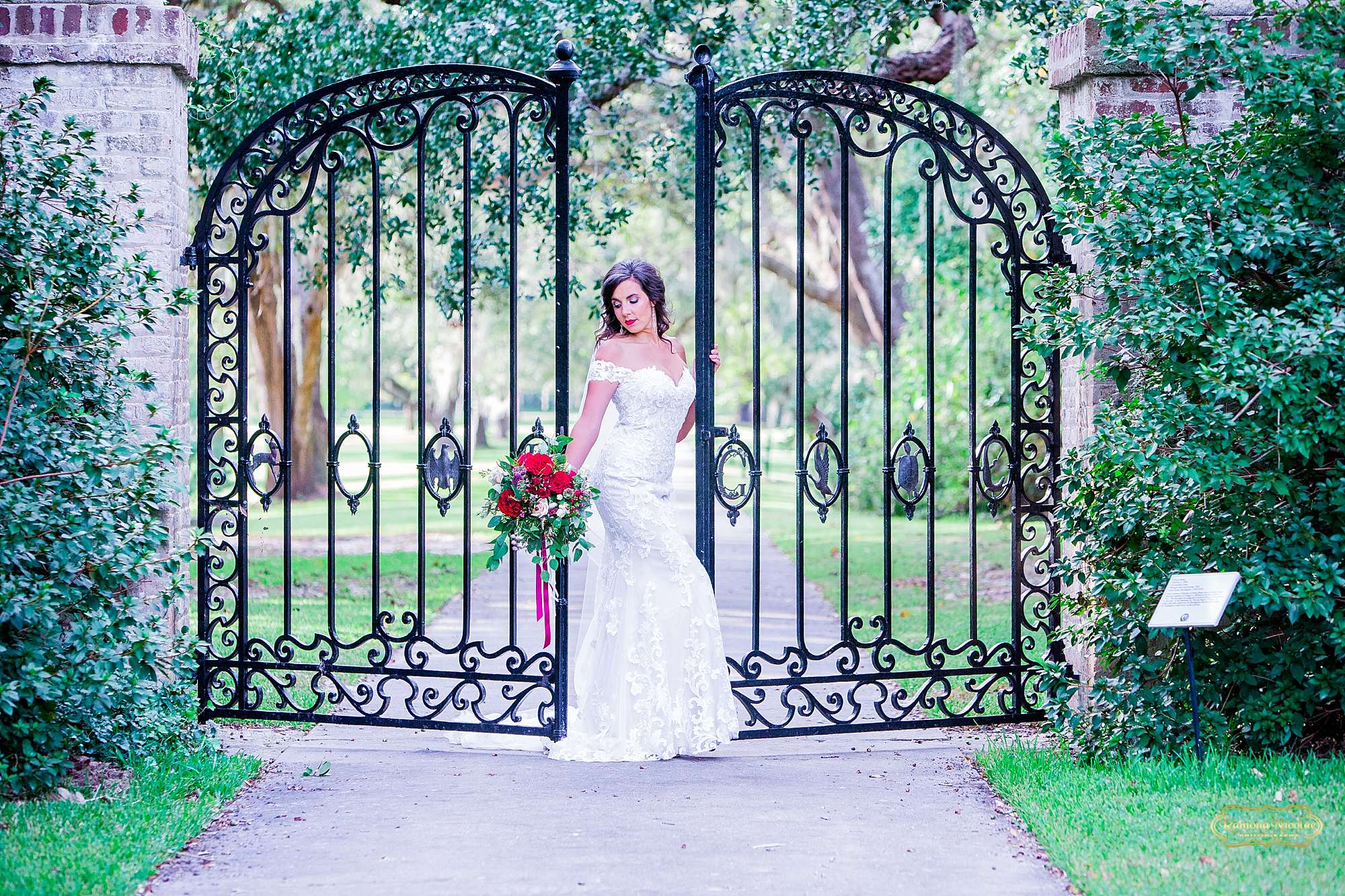 bride with red flowers by the black B & G gates at Brookgreen Gardens looking gorgeous during bridal session with ramona nicolae photography-12.jpg