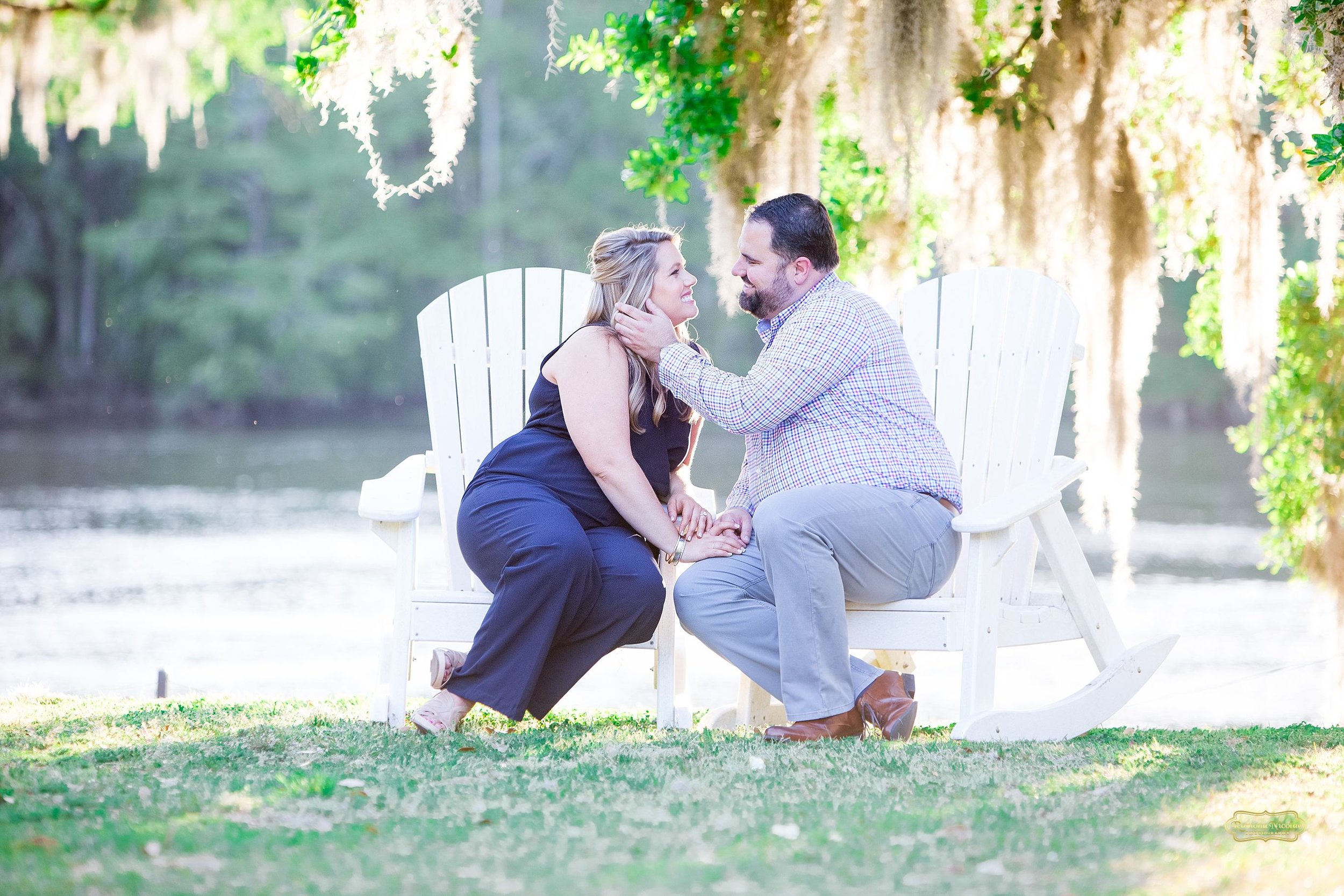 kissing on white rocking chairs for engagement shoot at wachesaw plantation.jpg