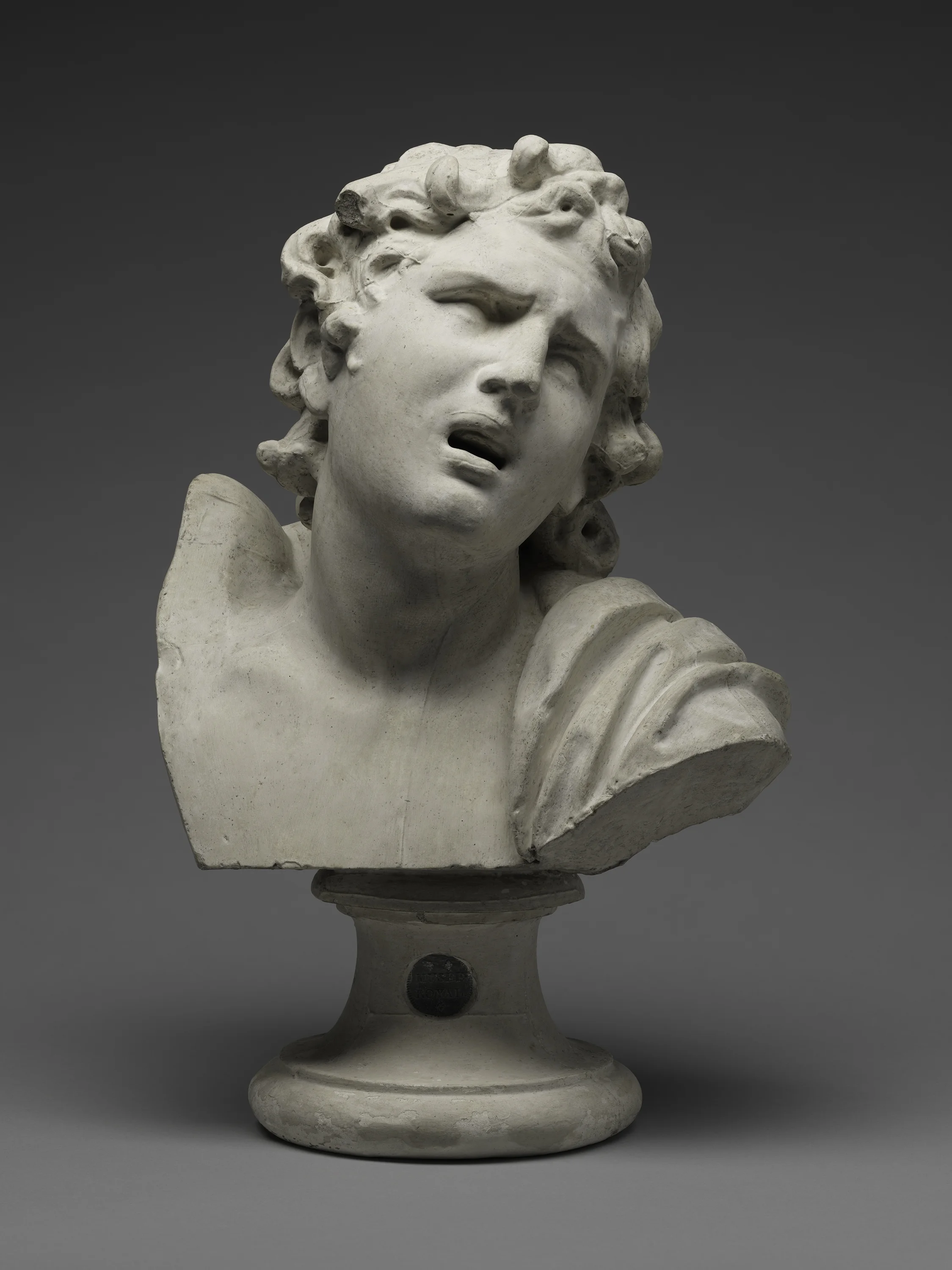 Marble bust sculpture of a woman's head and shoulders with her mouth open, on a pedestal with a circular base.