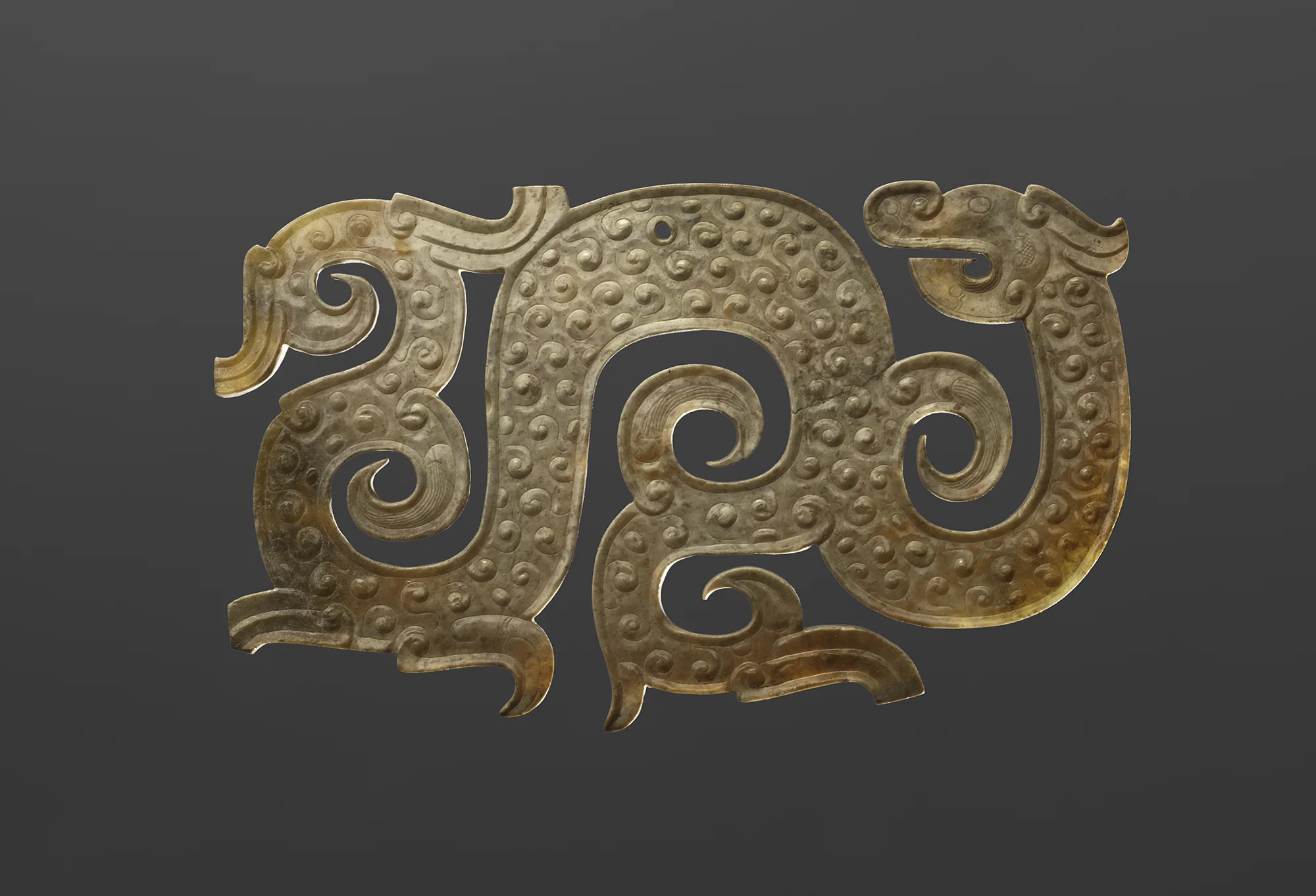 Decorative carved jade artifact with intricate swirling patterns.