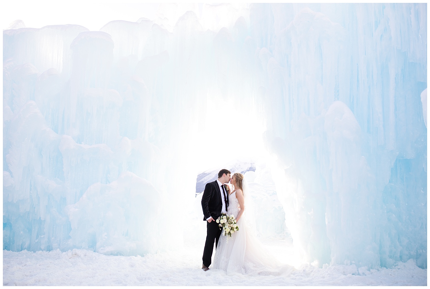 a bride and groom kiss underneath an arch made of ice at the Dillon Ice Castles in Colorado