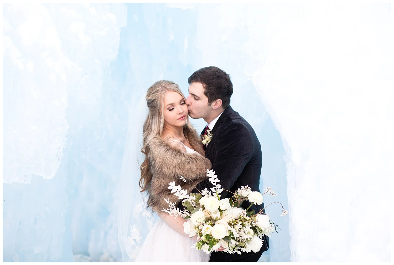 the groom kisses his bride’s cheek romantically