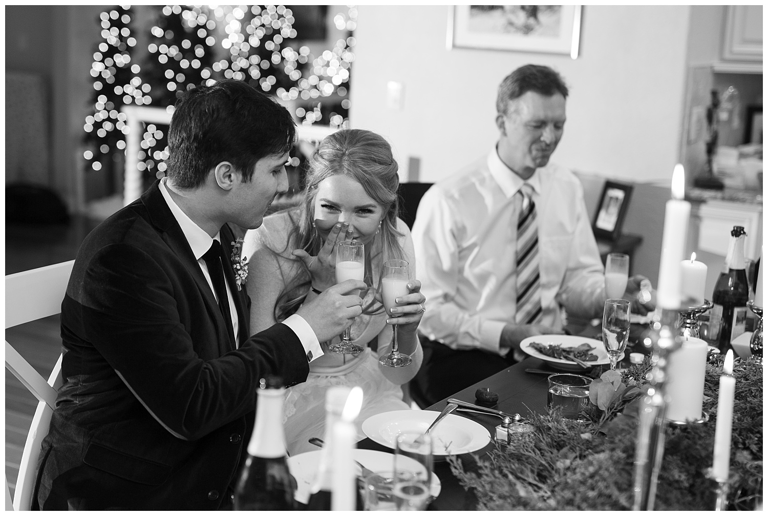 A bride laughs as she clinks glasses with her groom