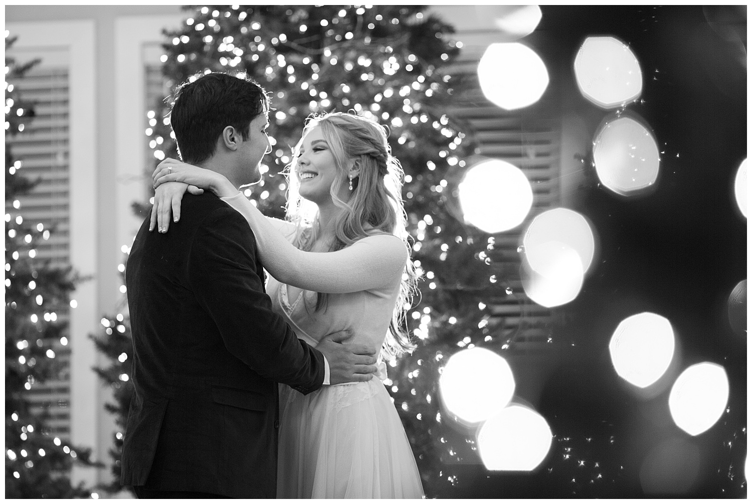 The bride is beaming at her husband while they dance in the middle of Christmas trees