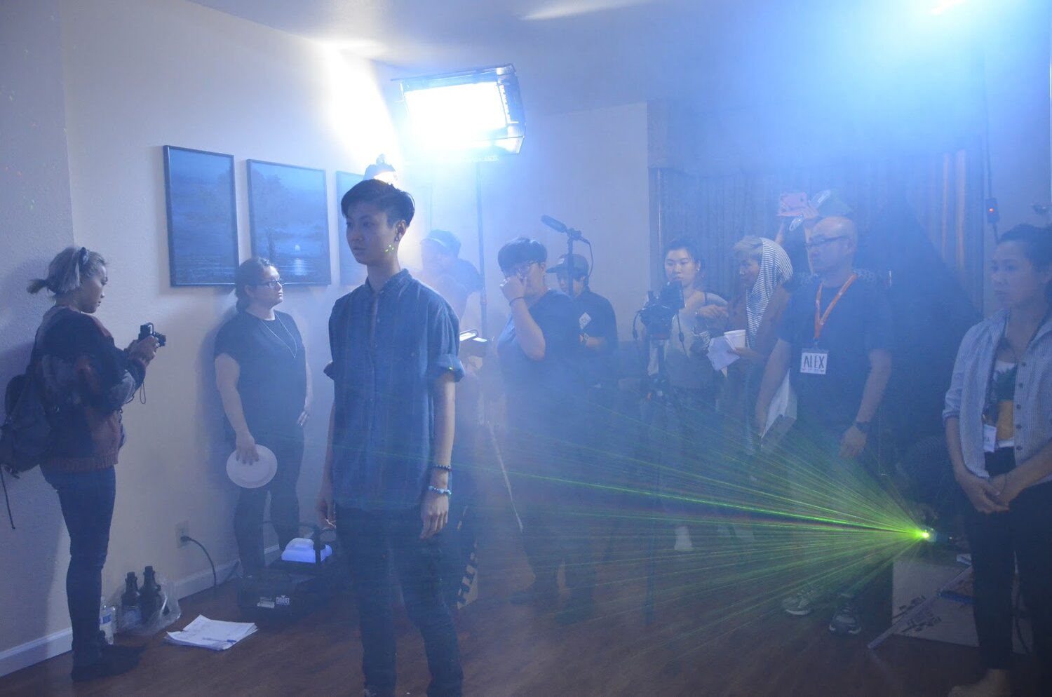  Actor Ck is standing in front of a film crew in a living room filled with fog and green lights. 
