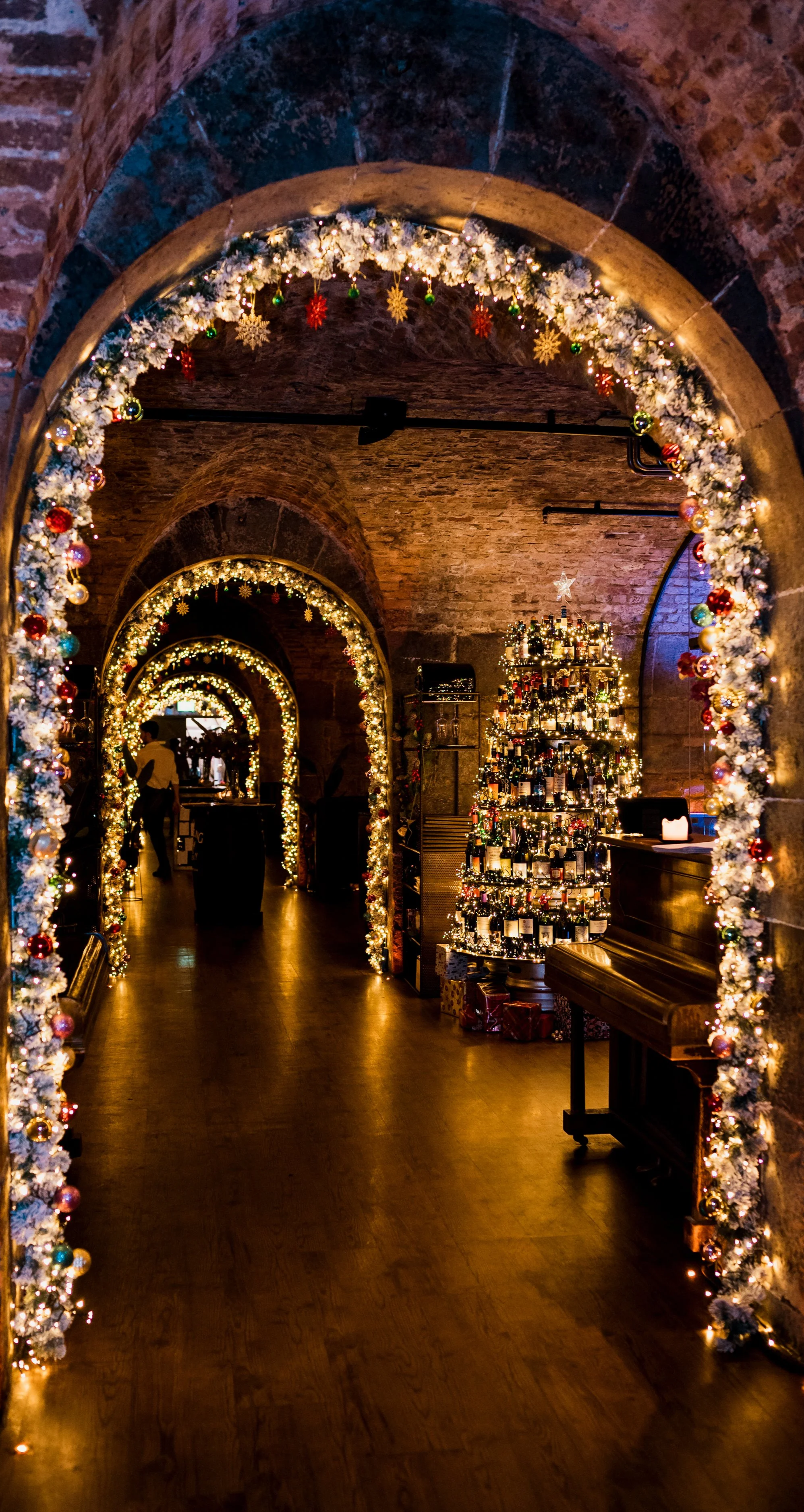 Vaulted brick archway decorated with Christmas lights and a lit Christmas tree at Urban Brewing Dublin