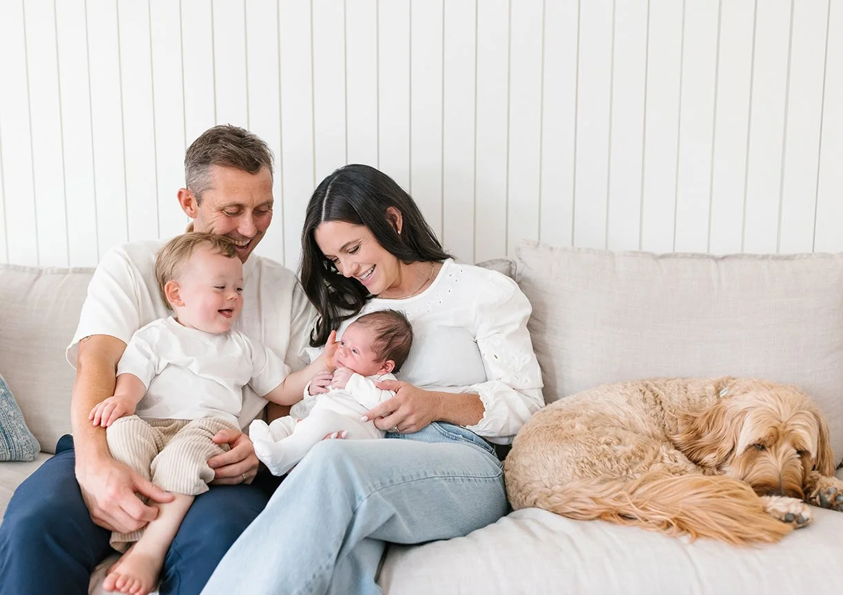 candid-family-portrait-with-newborn-toddler-and-dog-on-sofa.jpg