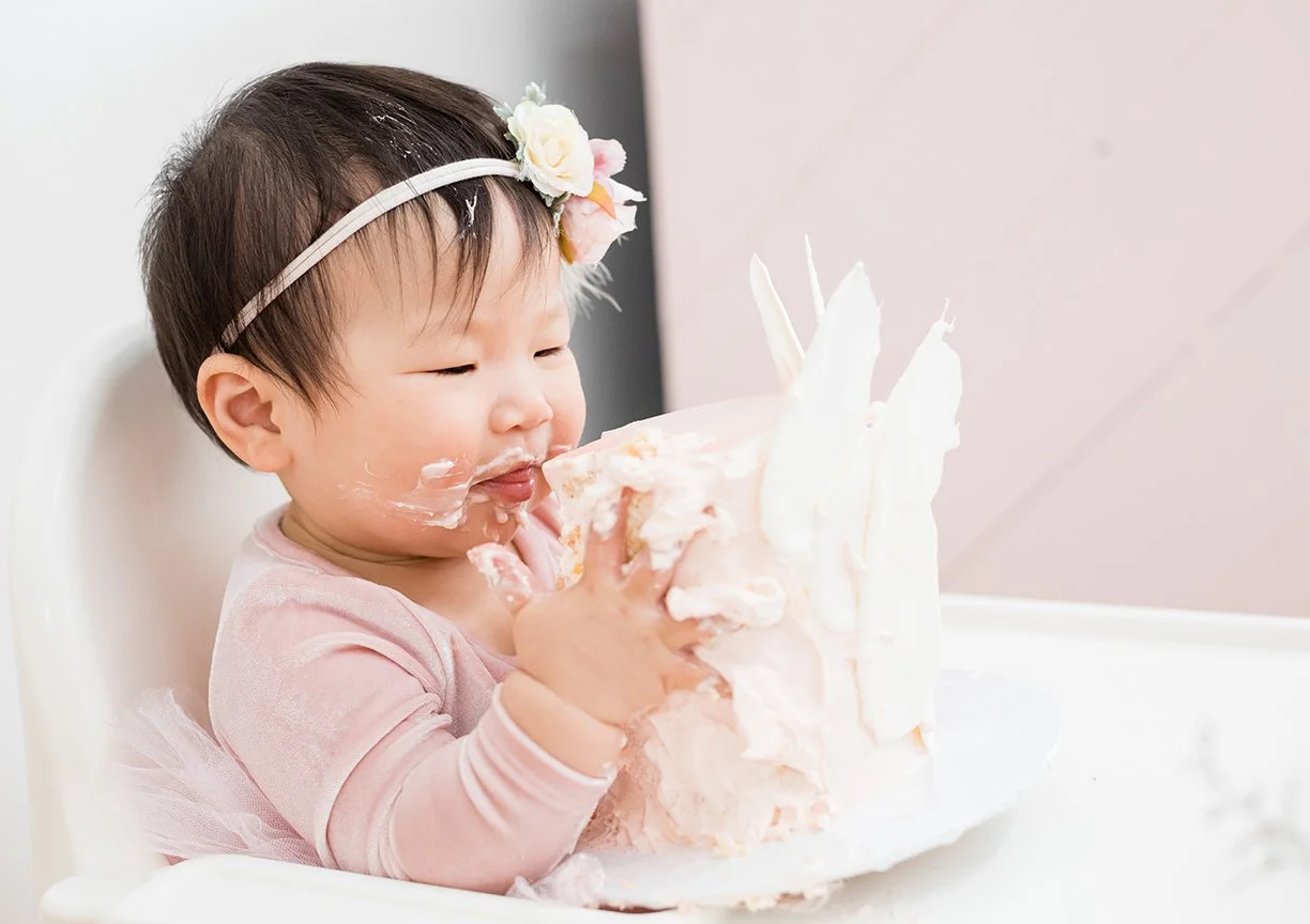 baby-girl-grabbing-birthday-cake-smiling.jpg