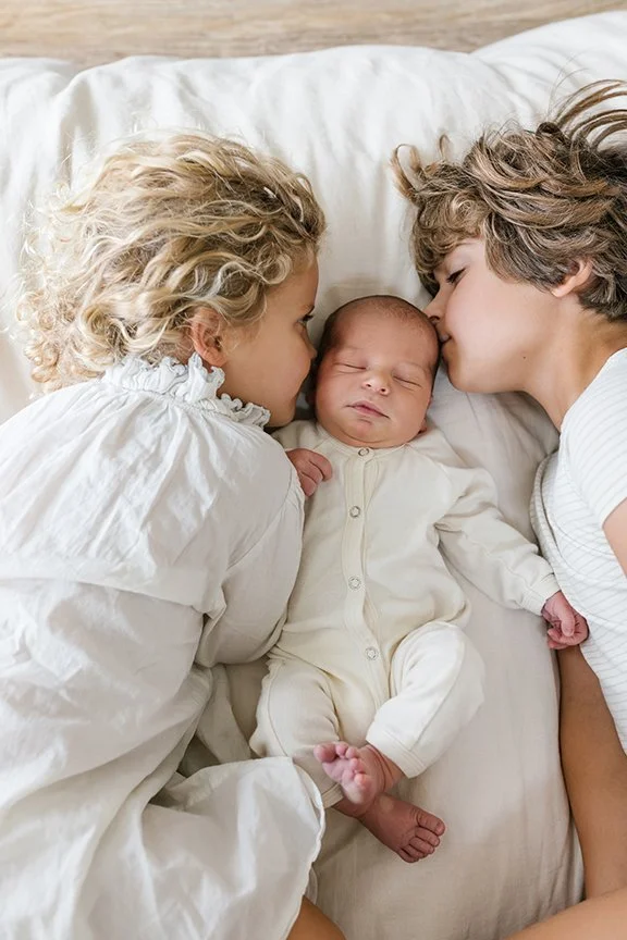 siblings-cuddling-newborn.jpg