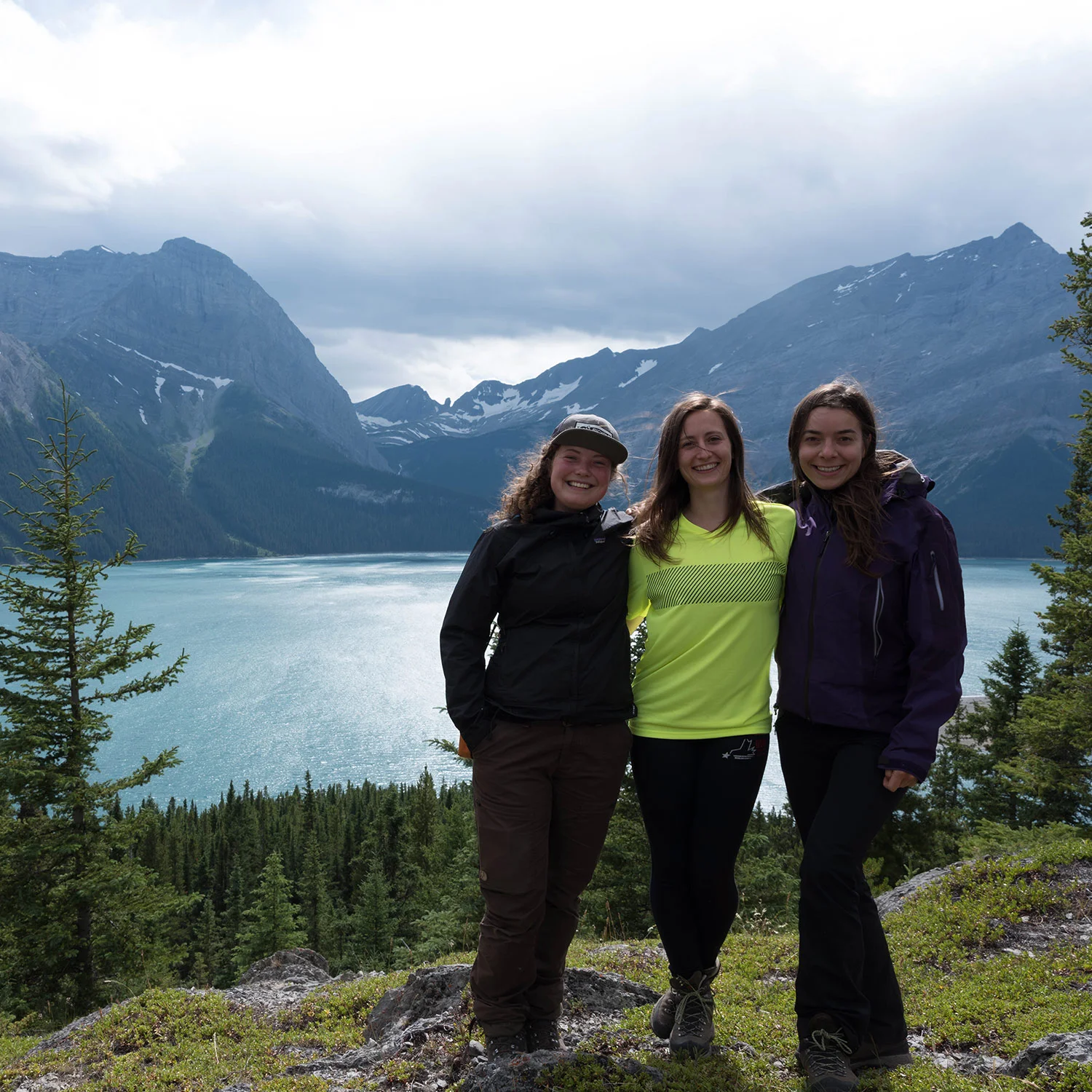 Navarana, Julie, and Sandra stop for a photo near a clear lake in the Rockies.