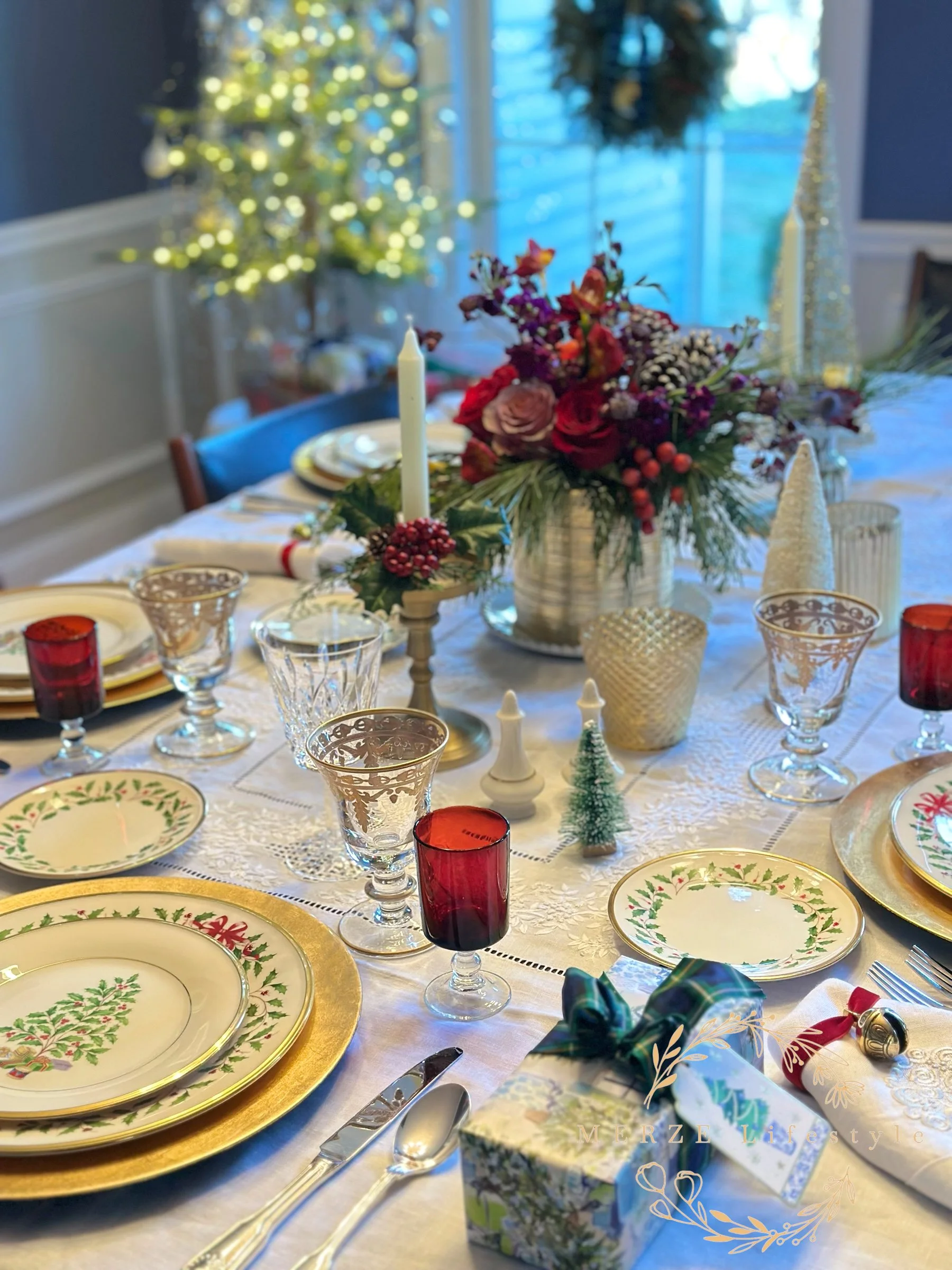 Traditional Christmas tablescape featuring Lenox holiday china, gold chargers, white linen tablecloth, vintage silver flatware, and a seasonal centerpiece.