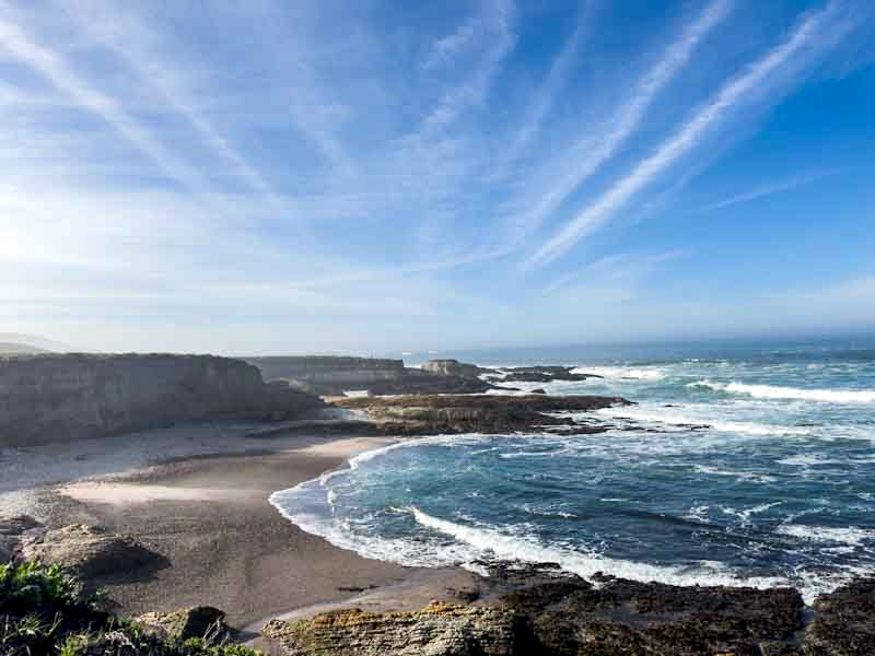 Wide view of California coastal cliffs overlooking the Pacific Ocean, layered in natural earth tones and deep blue water, representing reflection and restoration.