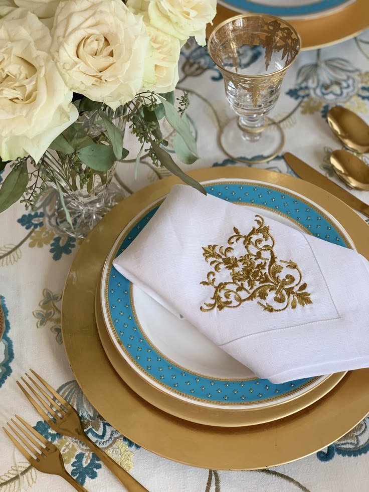 European linen napkin embroidered with Victorian motif styled within a layered place setting.