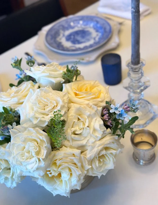 Antique Baccarat crystal candleholder with white and cream florals on a layered blue and white table setting.
