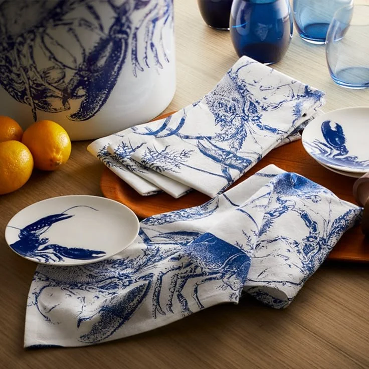 Blue lobster cotton napkins styled with plates on a table, creating a relaxed coastal and gathered table setting