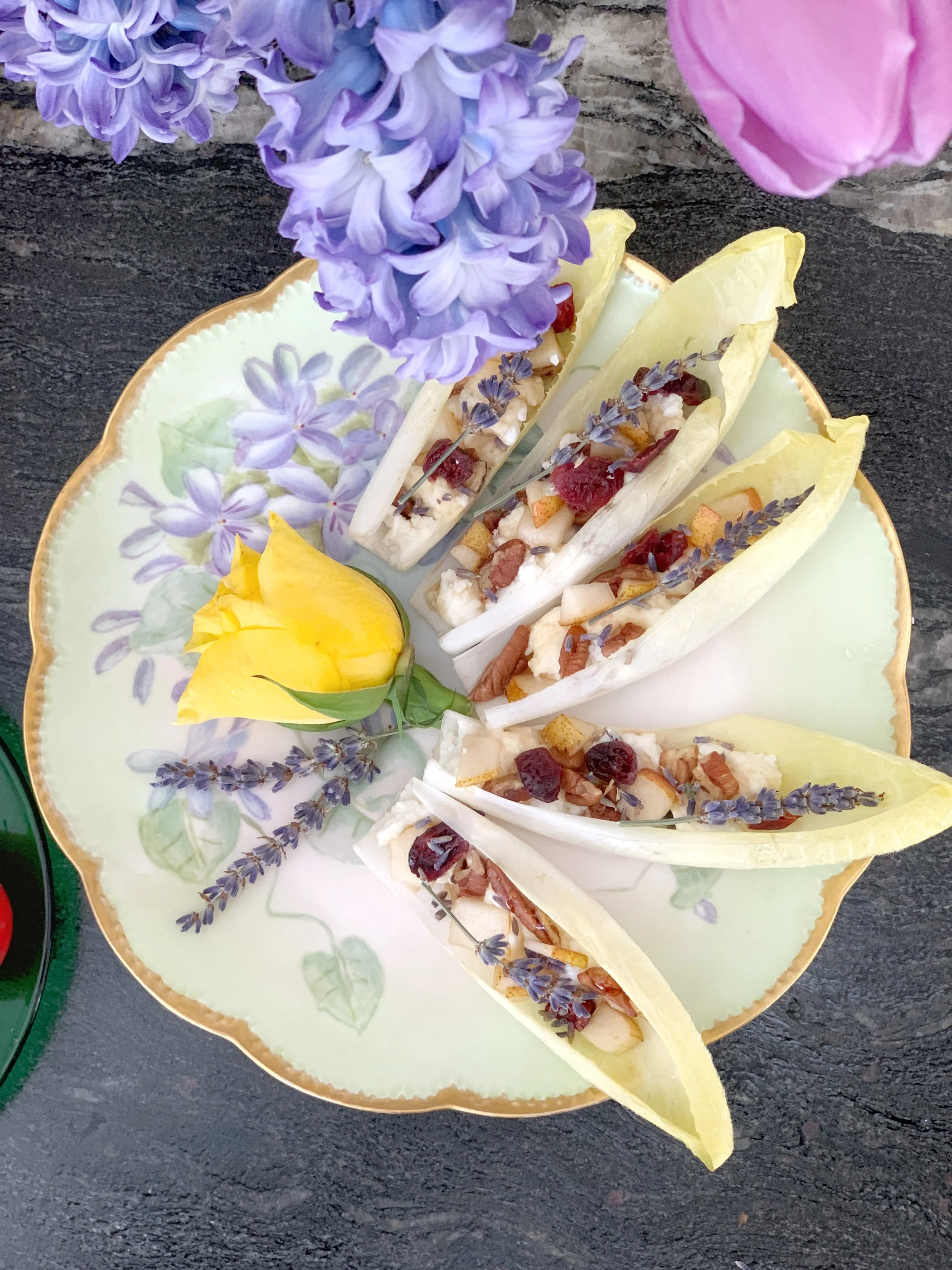 Elegant endive appetizer filled with lavender goat cheese, pear, pecans, and cranberries, garnished with fresh lavender and a yellow rose for a spring Easter table.