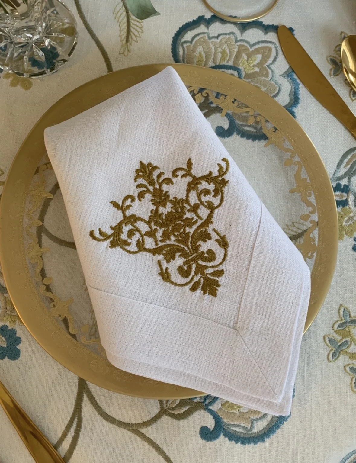 Glass dinner plate with gold rim styled beneath antique porcelain bowl in an elegant table setting.