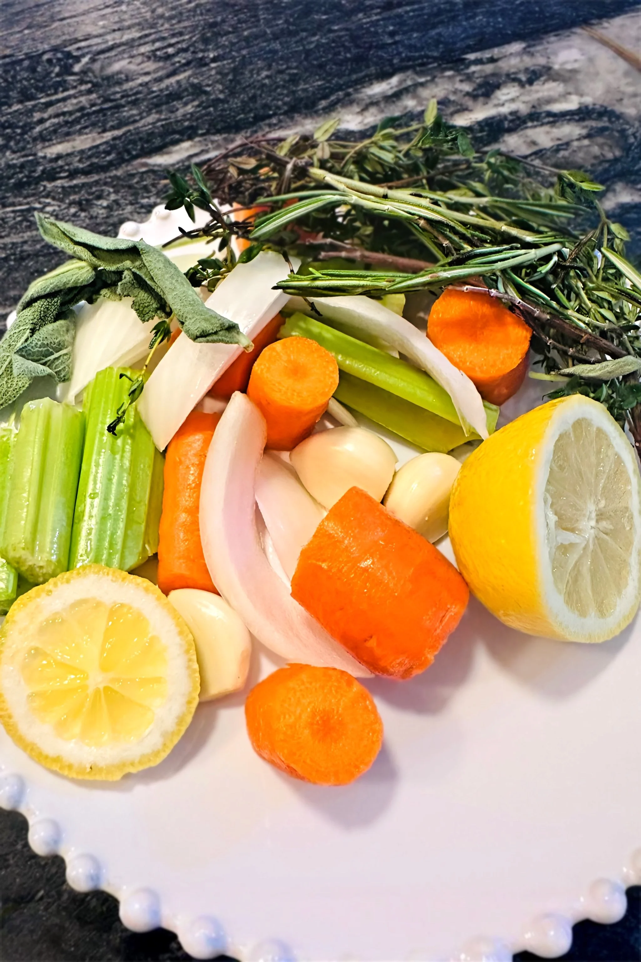 Bouquet garni with fresh thyme rosemary and sage alongside celery carrot lemon and garlic for stuffing a French roast chicken — Merze Lifestyle
