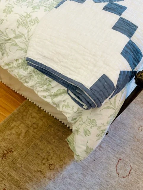 A light green bed skirt trimmed with cream pom-poms, echoing the green and cream tones of the toile bedding above.