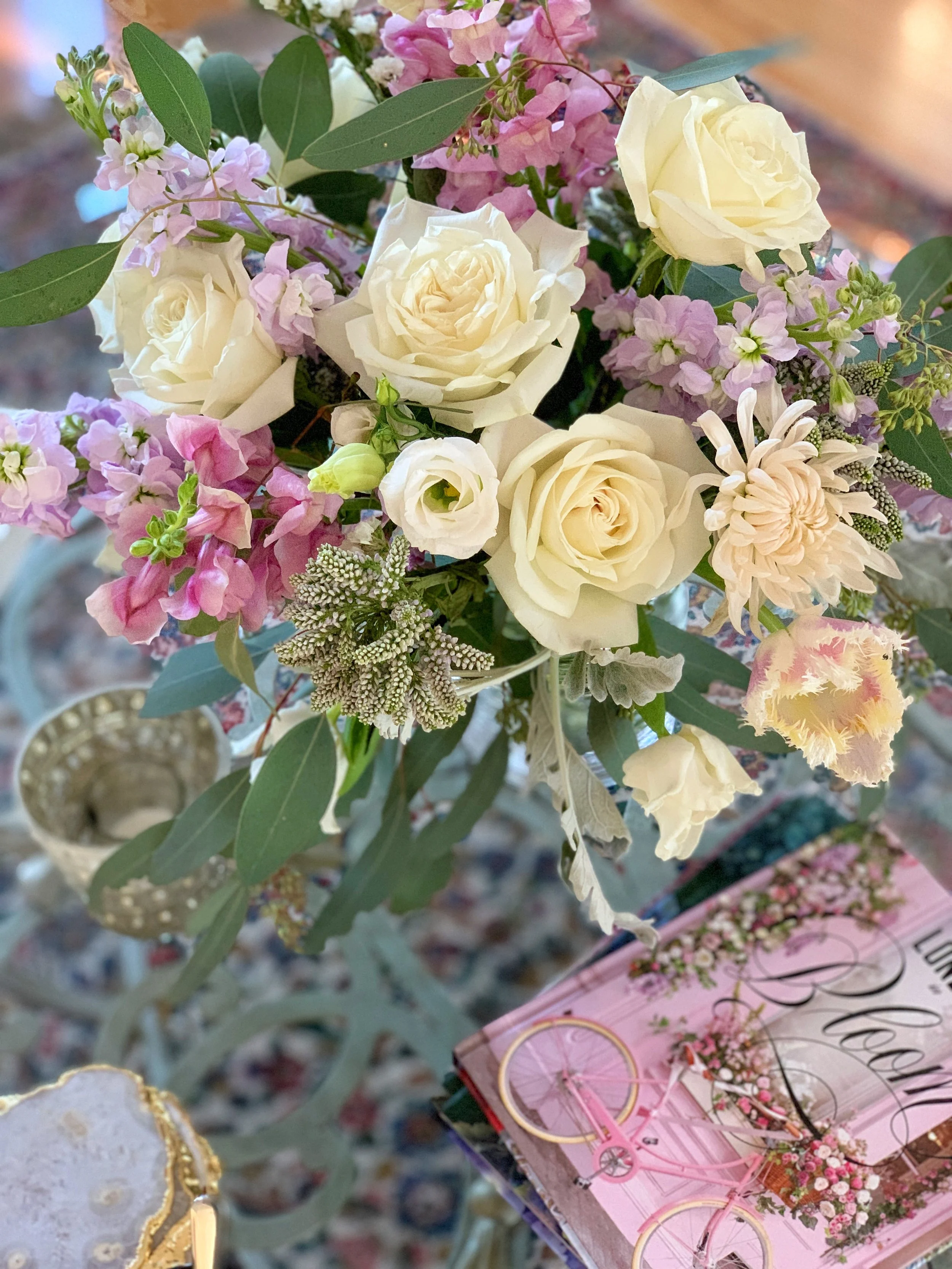 Spring floral centerpiece resting on a glass table with London in Bloom book by Georgianna Lane as part of a decorative spring entertaining vignette