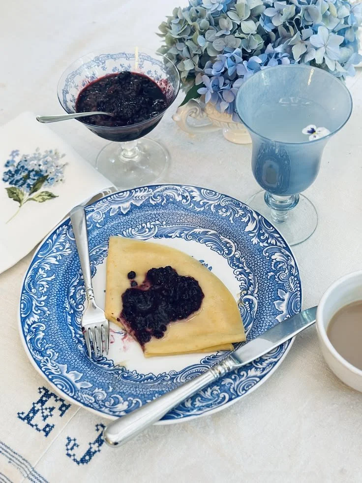 Brunch for two on antique French linen with an embroidered hydrangea napkin, blue and white transferware, and a café au lait cup