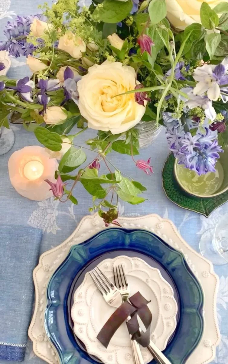 Elevated French coastal tablescape in jewel tones with a cobalt glazed plate, candlelight, raw silk ribbon, and loose garden flowers