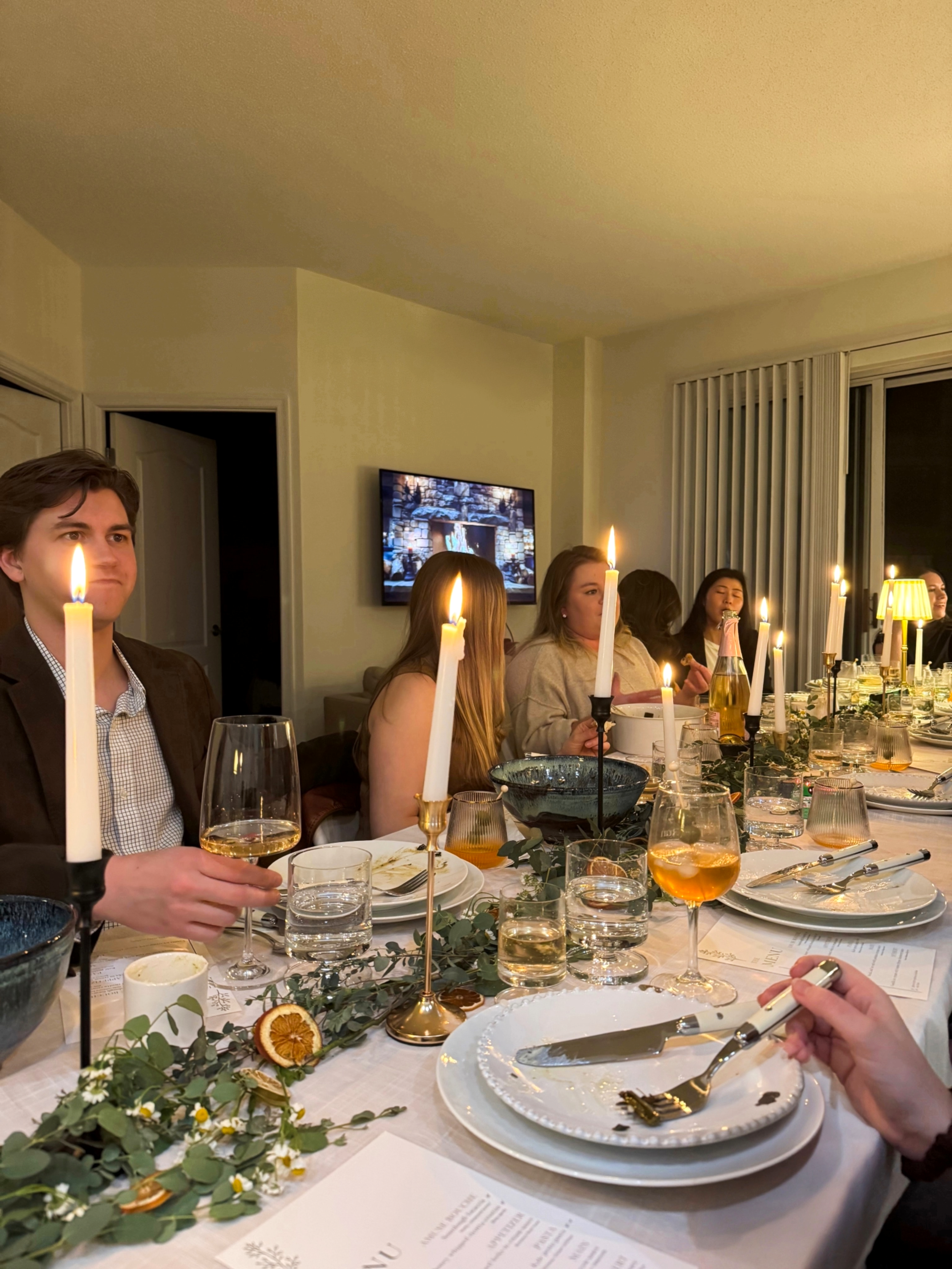 Group of friends seated closely around a candlelit dinner table in an intimate Washington condominium setting.
