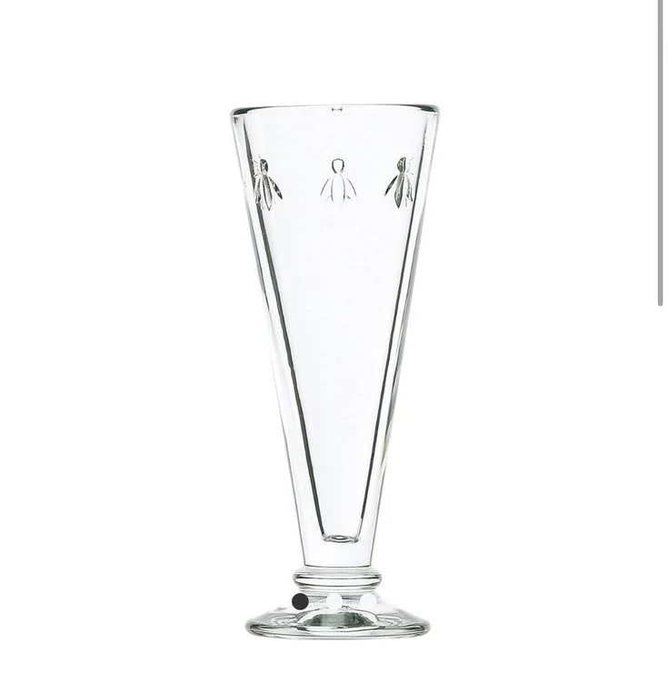 Single French bee champagne glass with a tall flared silhouette and embossed bee motif, shown on a white background.