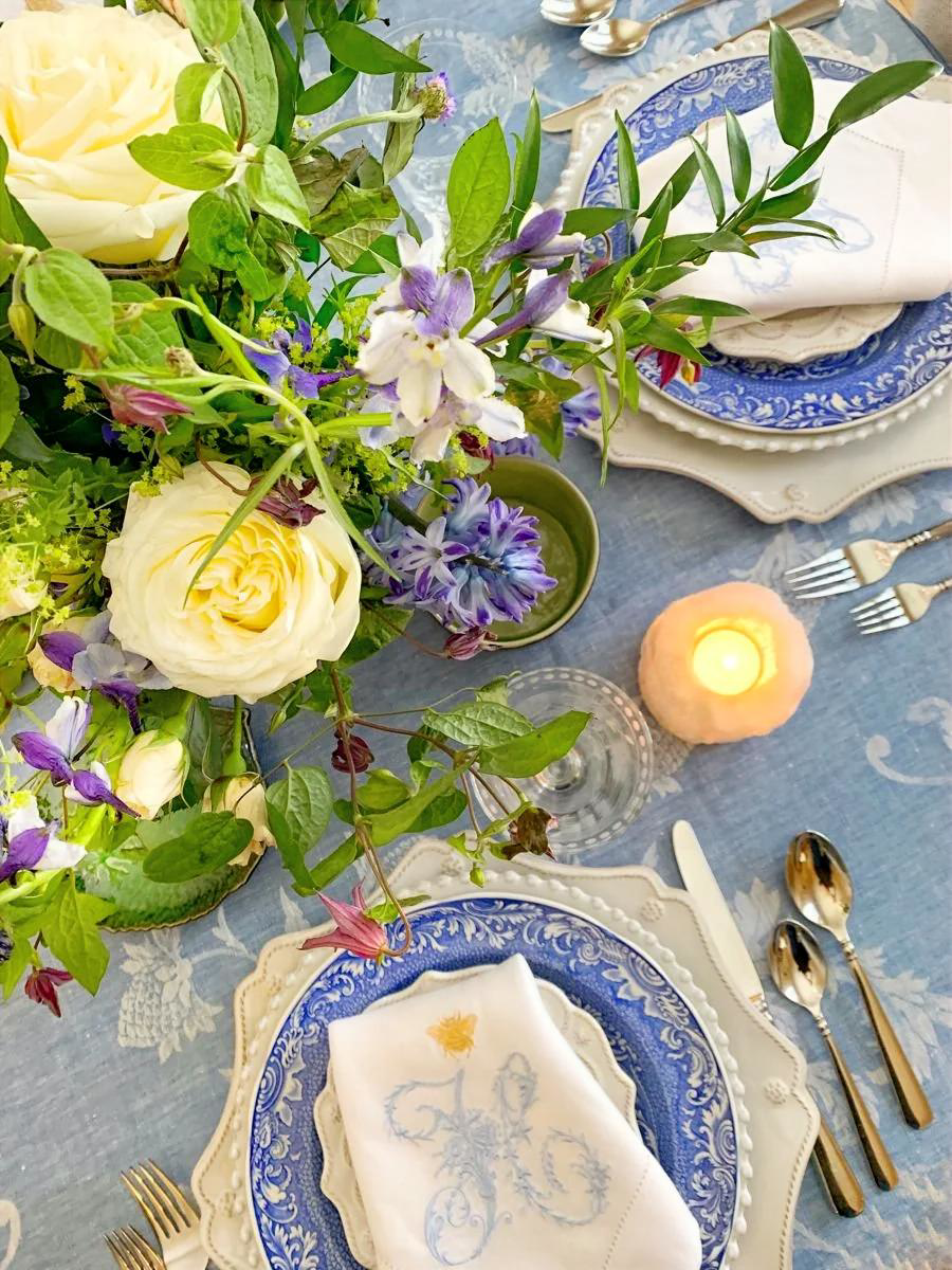 French coastal blue and white vintage china table setting with floral centerpiece and candlelight.