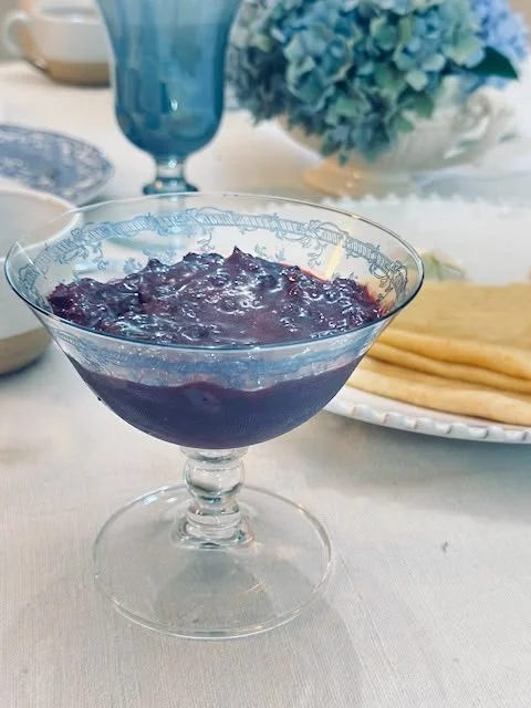 Berry compote served in an etched glass compote dish on a French linen table