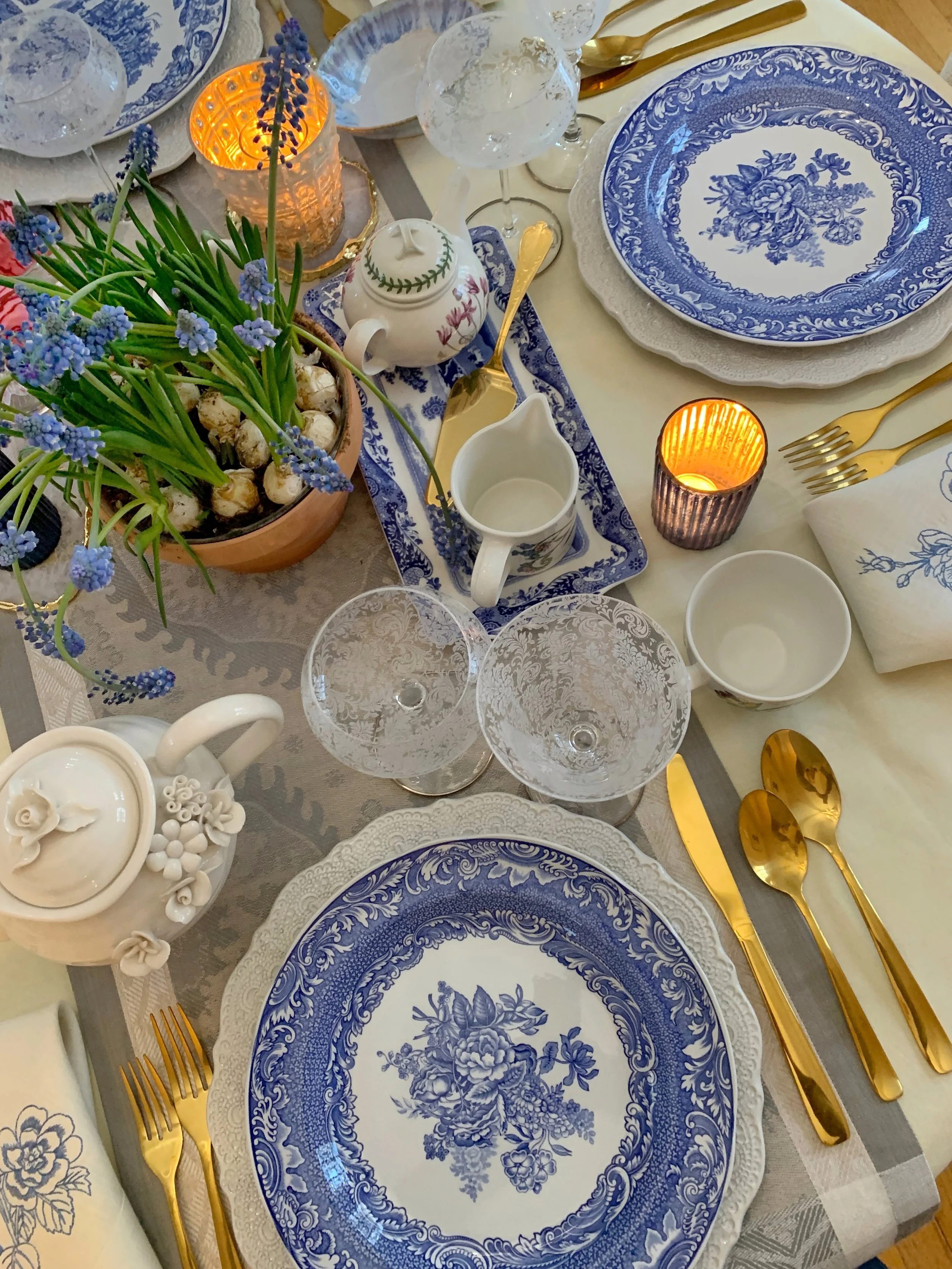 layered spring table showing spode plates with portmeirion china cream and sugar set and grape hyacinth centerpiece
