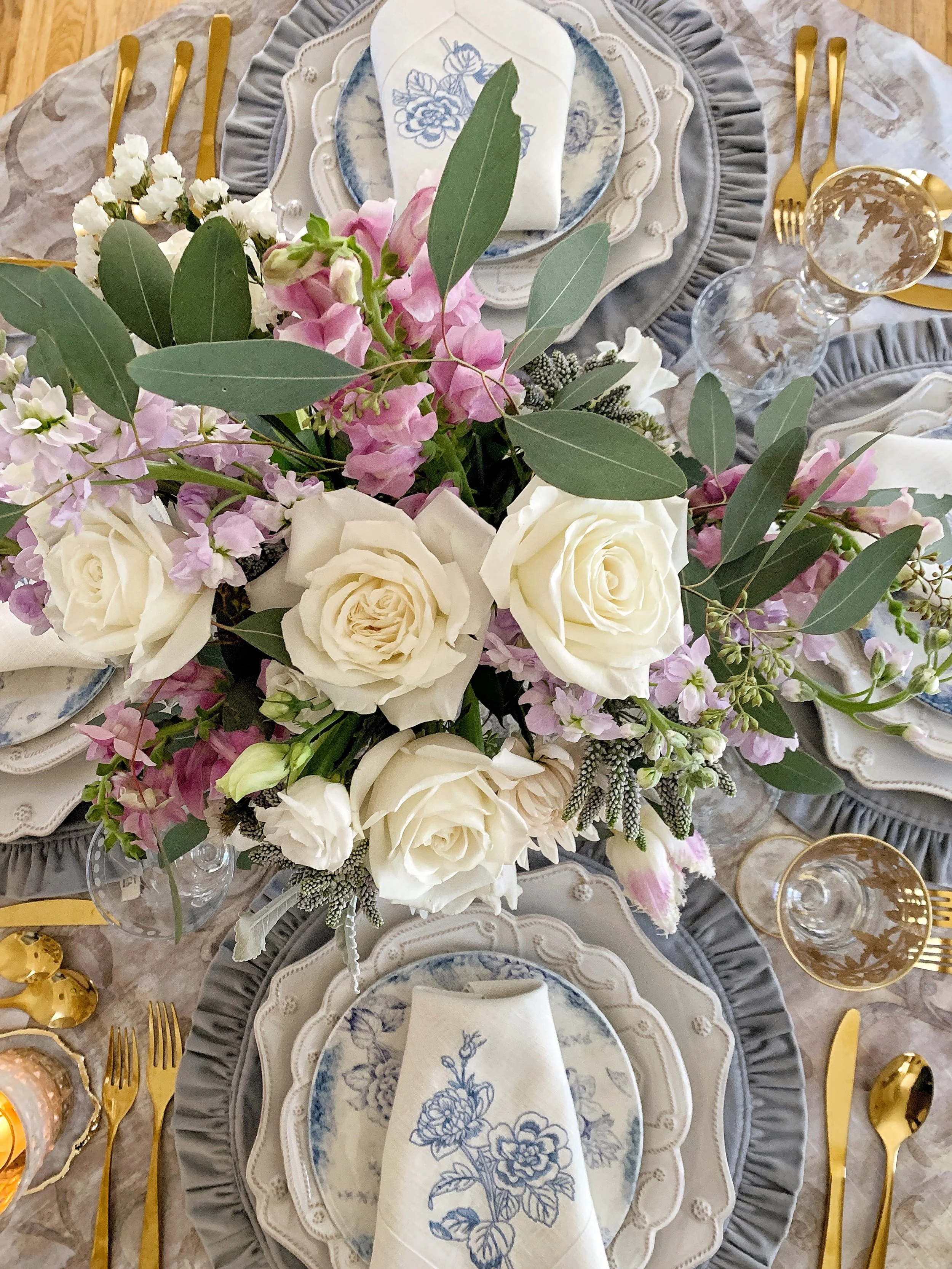 Aerial view of a Mother's Day tablescape showing two place settings with Juliska Berry chargers Arte Italica accent plates velvet gray ruffled placemats and spring floral centerpiece
