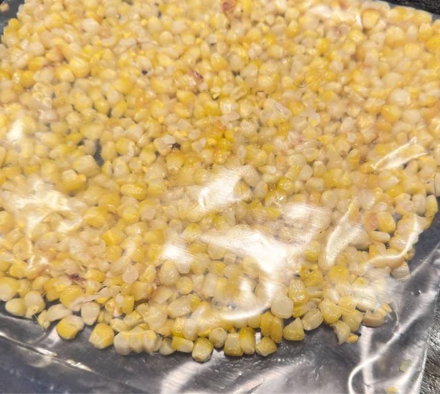 Roasted corn kernels packed flat in a freezer bag for winter soups