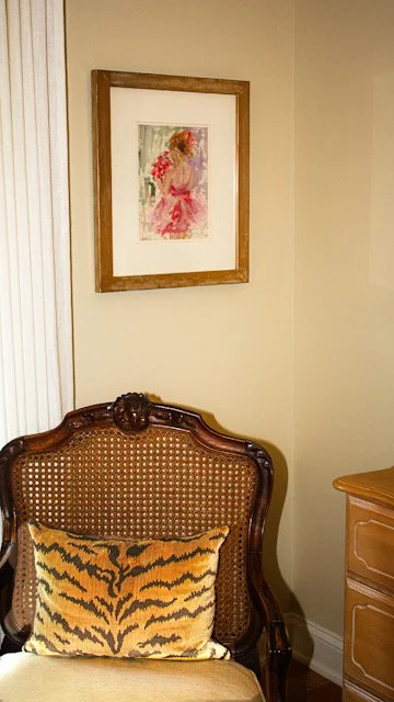 A watercolor painting of a young ballerina in a pink tutu with a ballet bun, framed in a hand-gilded gold frame.