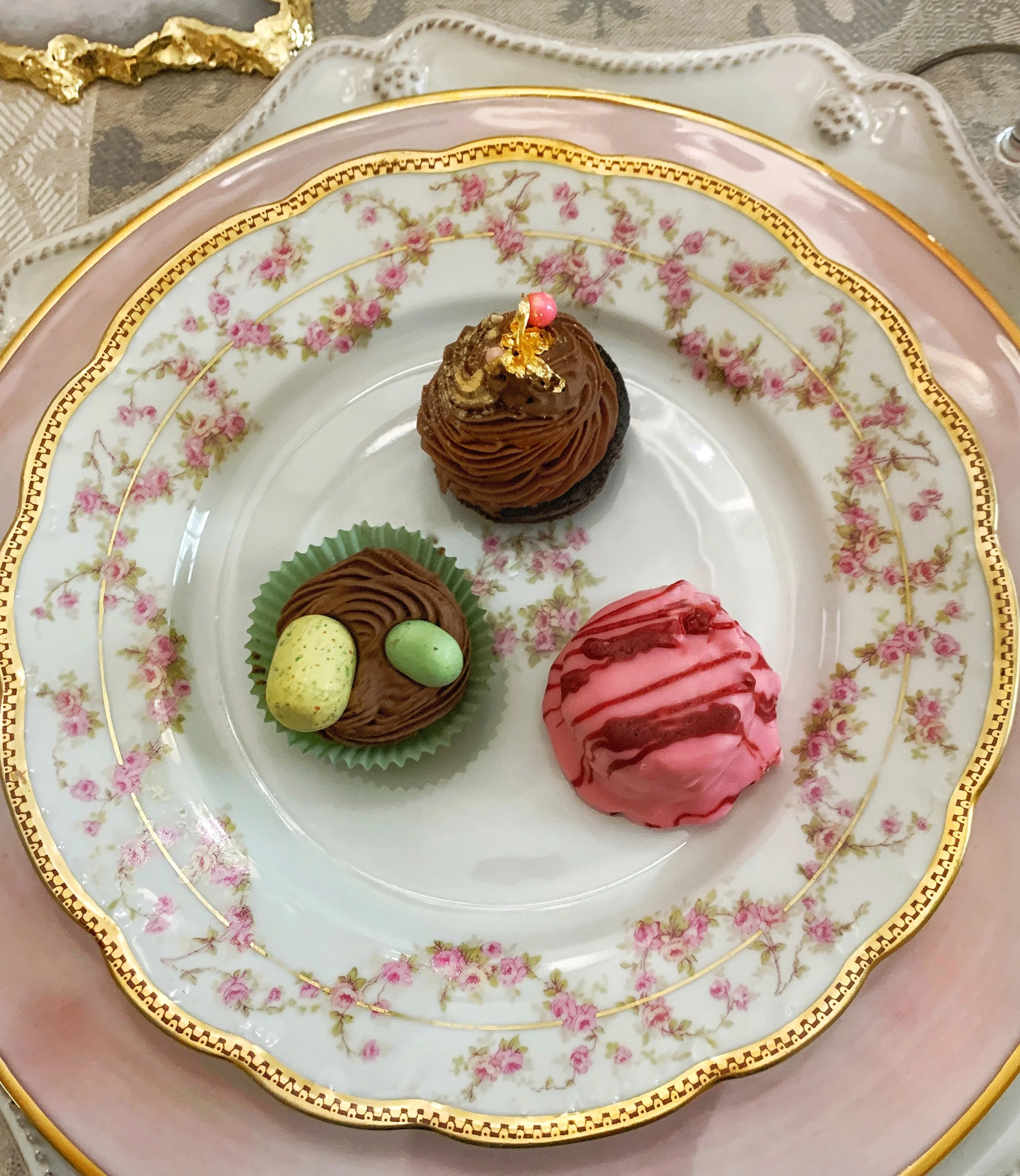 Selection of three small desserts served on vintage Limoges china, styled for an elegant Easter high tea gathering.