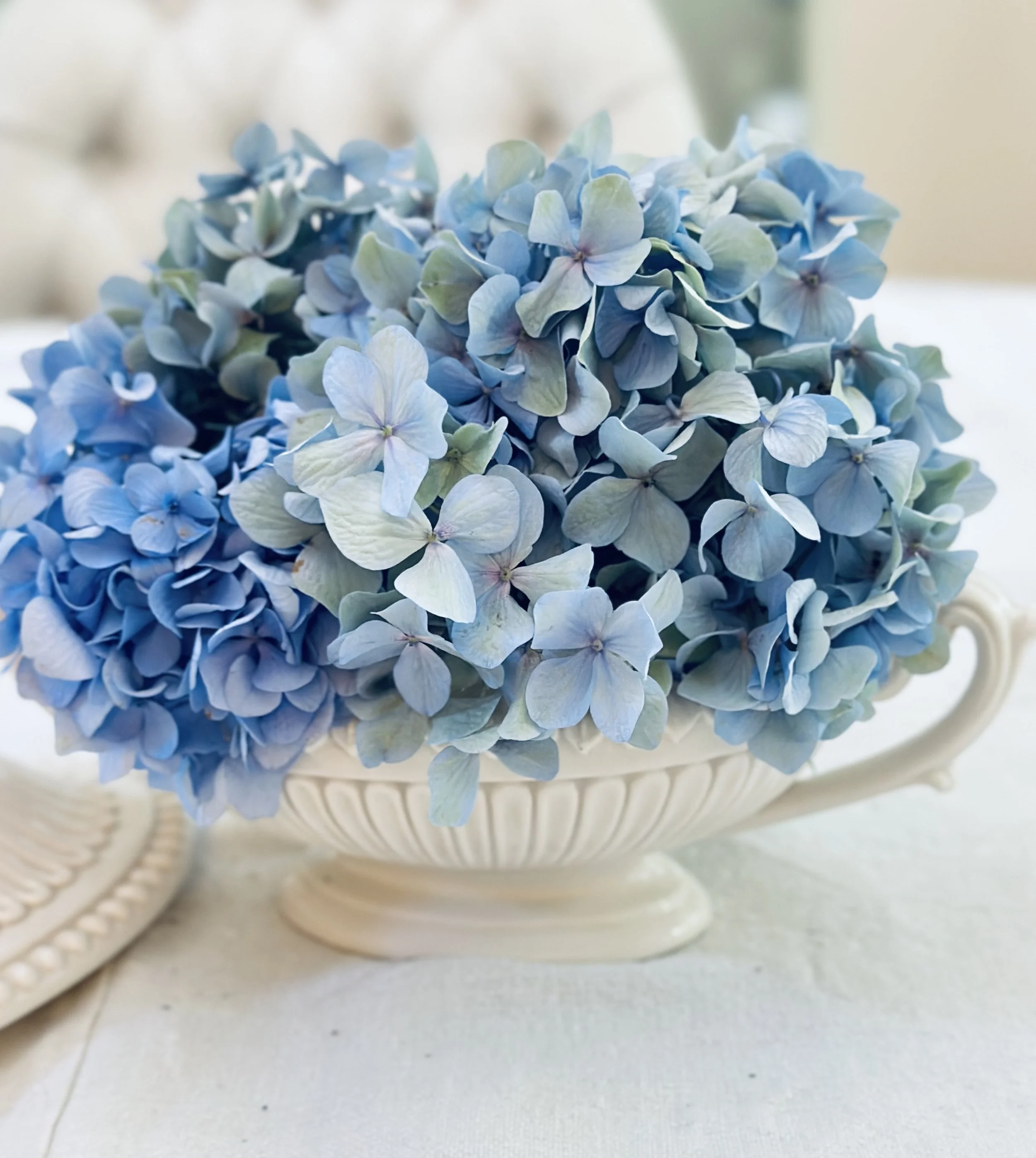 A cream soup tureen filled with blue hydrangeas as a summer table centerpiece