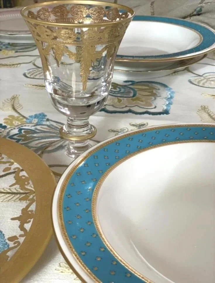 Antique porcelain bowl with aqua rim and raised gold dots styled in an elegant layered place setting.