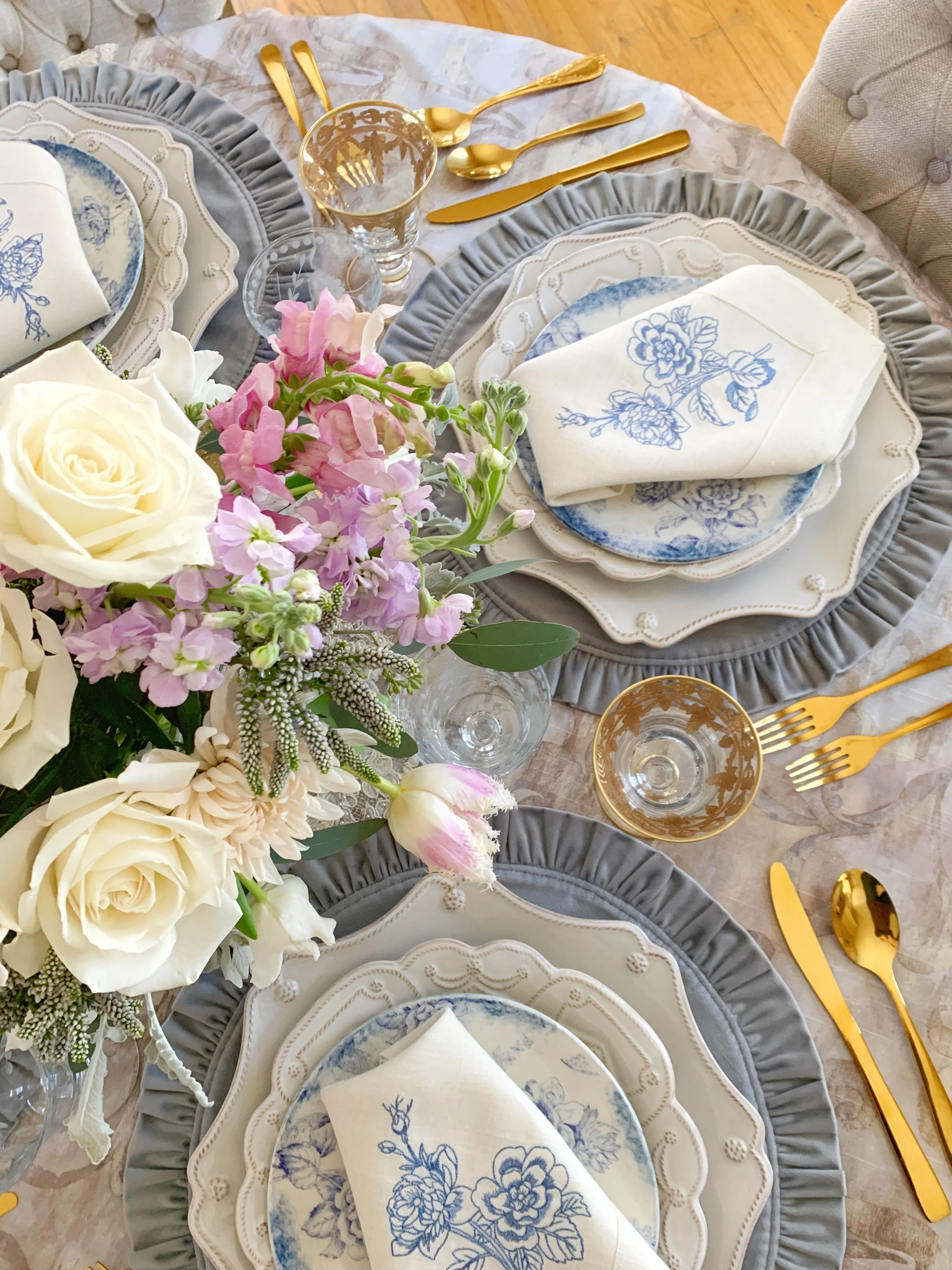 Side aerial view of a spring Mother's Day tablescape with velvet gray ruffled placemats French Jacquard linen tablecloth etched gold Arte Italica wine glasses Juliska Berry chargers and spring floral centerpiece