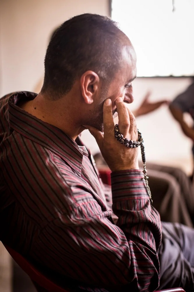 An Iraqi man sits in a men’s group therapy session at the Collateral Repair Project community center in Amman, Jordan. The men pass around a string of prayer beads and take turns sharing whatever is on their mind, giving them an outlet to deal with trauma they’ve witnessed, or the frustrations of not being able to work in Jordan.