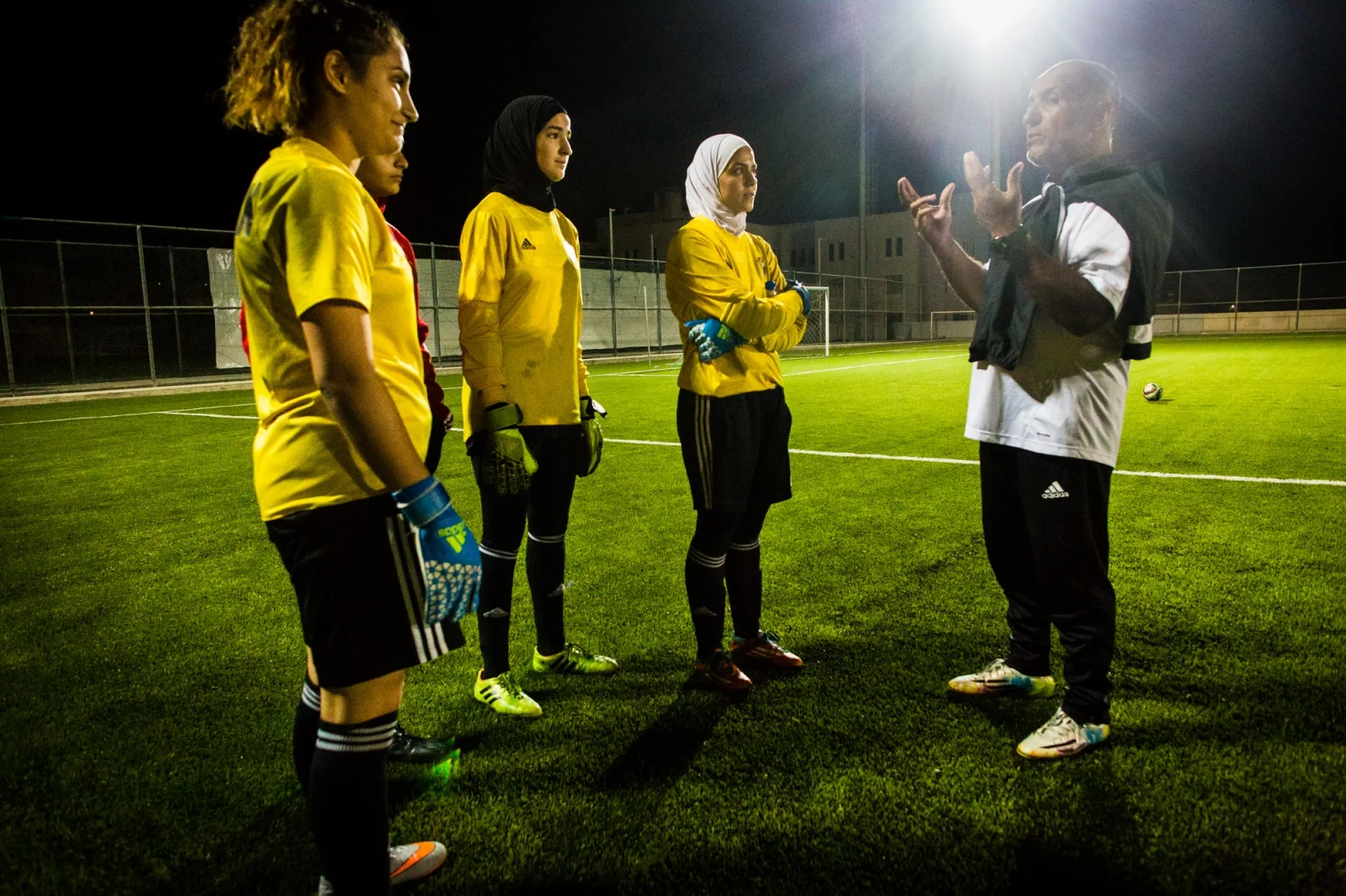 Rand al-Bustanji (2nd left) and her teammates listen to their coach at a practice session at Sports City in Amman, Jordan.